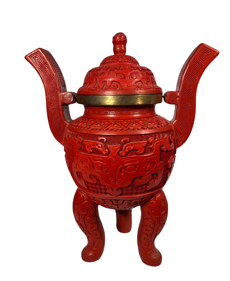 Chinese Carved Red Lacquer Tripod Censer with Archaistic Taotie Motifs: A Chinese covered tripod censer modeled in the form of an archaic bronze ritual vessel. The deep red lacquered body is carved in relief with stylized taotie masks, cloud scrolls, leiwen, and geometric