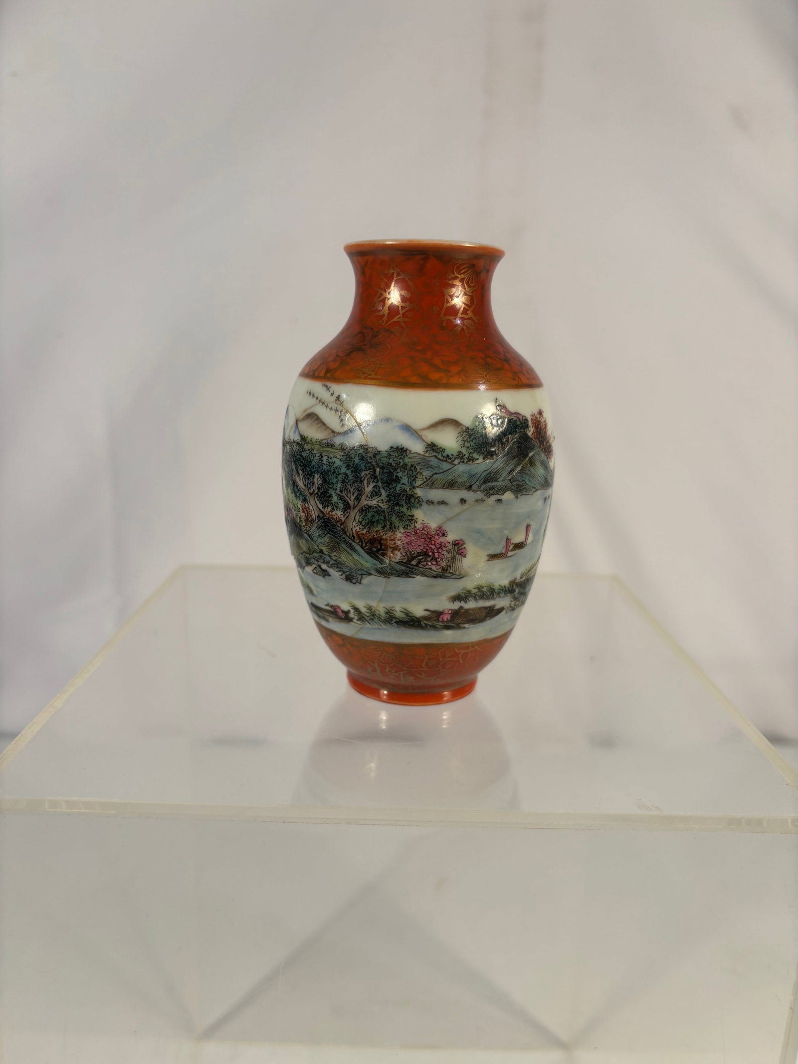 A Chinese famille rose red-ground scenic cabinet vase, Shendetang mark: A finely painted Chinese porcelain cabinet vase decorated in famille rose enamels. The vase features a rich iron-red ground with gilt floral scroll decoration to the neck and foot, surrounding a conti