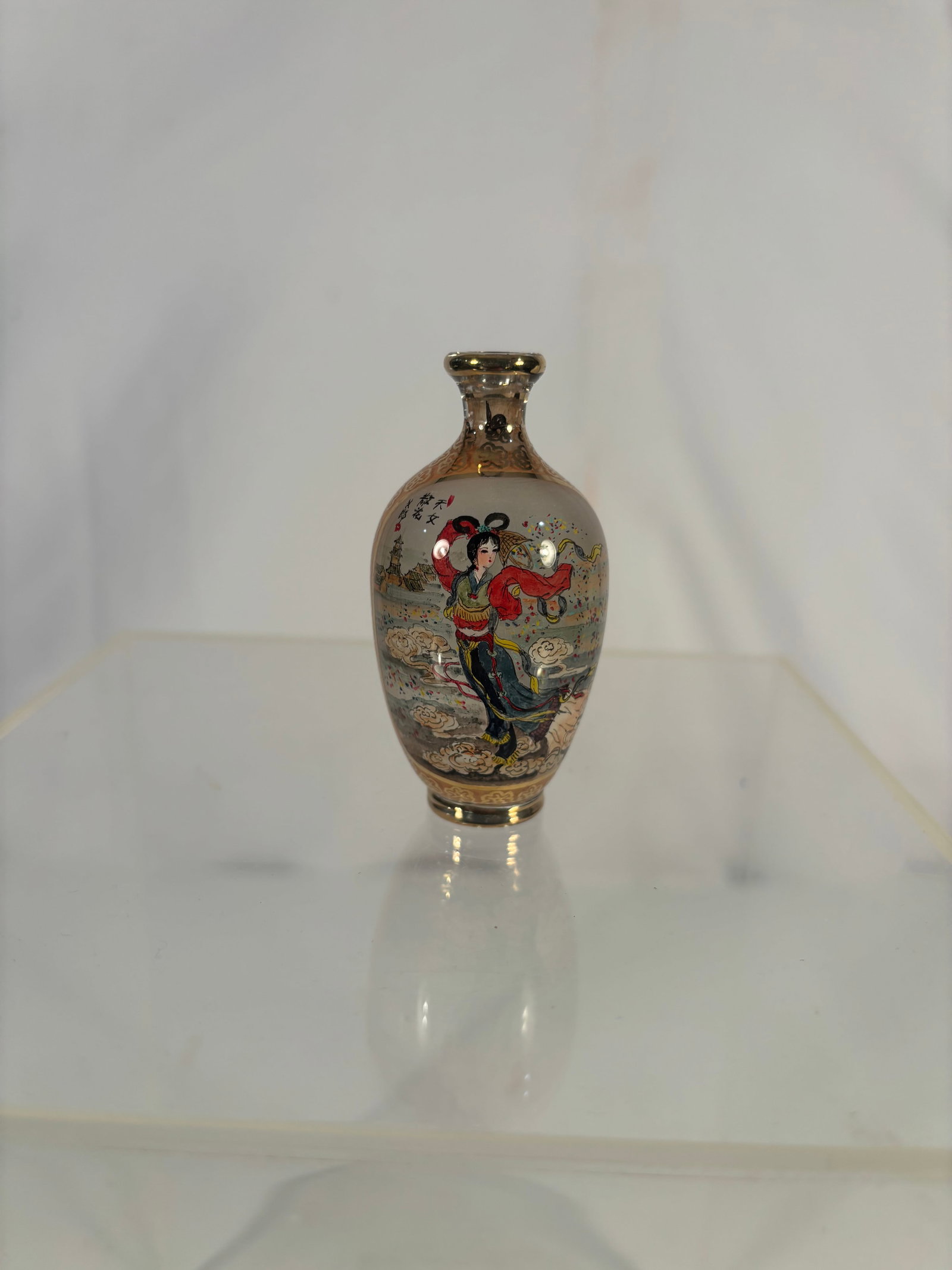 A Chinese Gilt Decorated Inside Painted Glass Snuff Bottle, Landscape & Immortal Figure: A Chinese inside-painted glass snuff bottle of flattened baluster form, finely decorated with gilt scrolling borders and a gilt rim. One side painted with a mountainous landscape featuring pavilion an