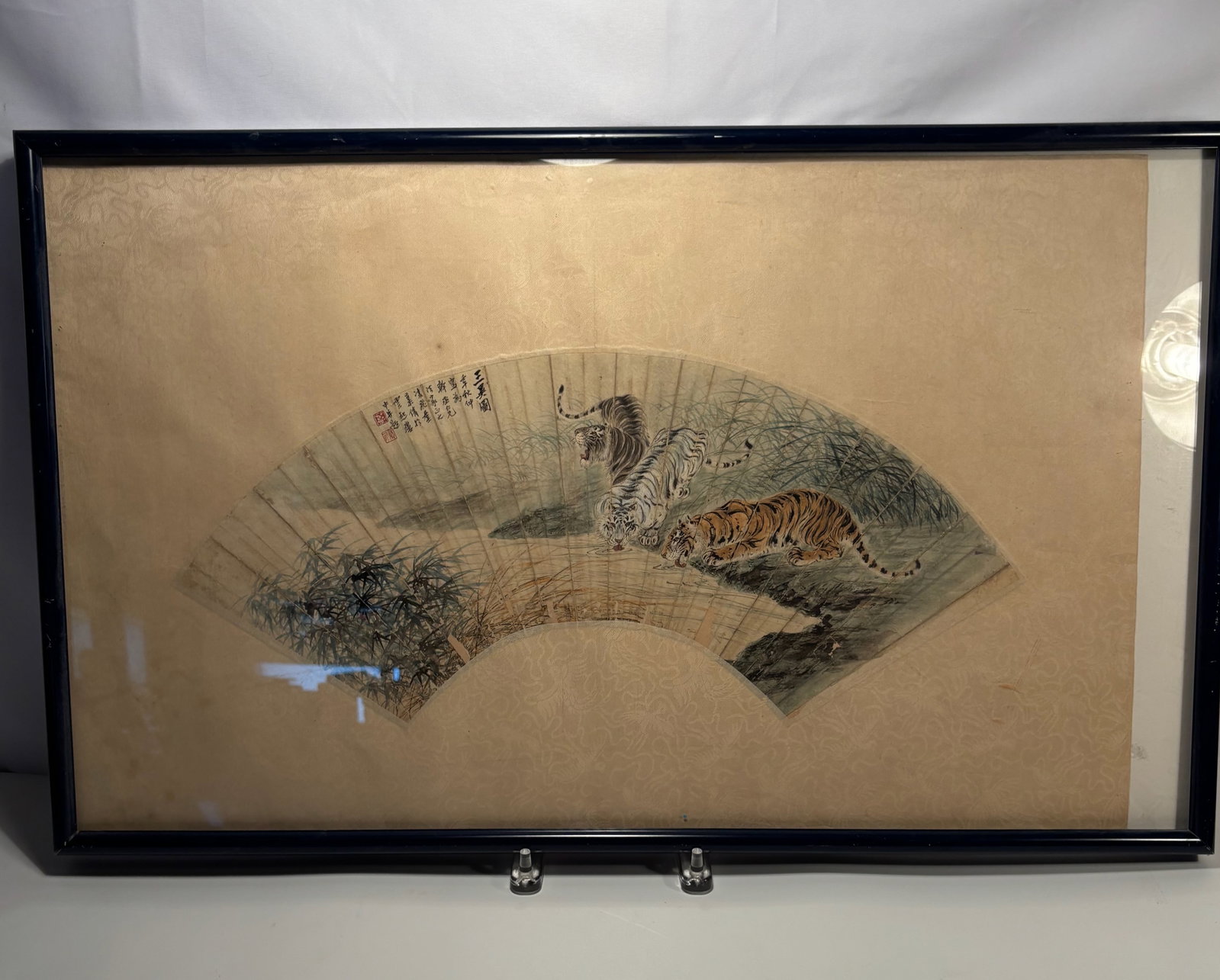 A Chinese Fan Painting of Three Tigers in Landscape, Ink and Color on Paper,: Qing Dynasty (1644-1912); A finely painted Chinese fan-shaped composition, depicting three tigers—one white and two striped—prowling among grasses beside rocks. Executed in ink and color on paper,