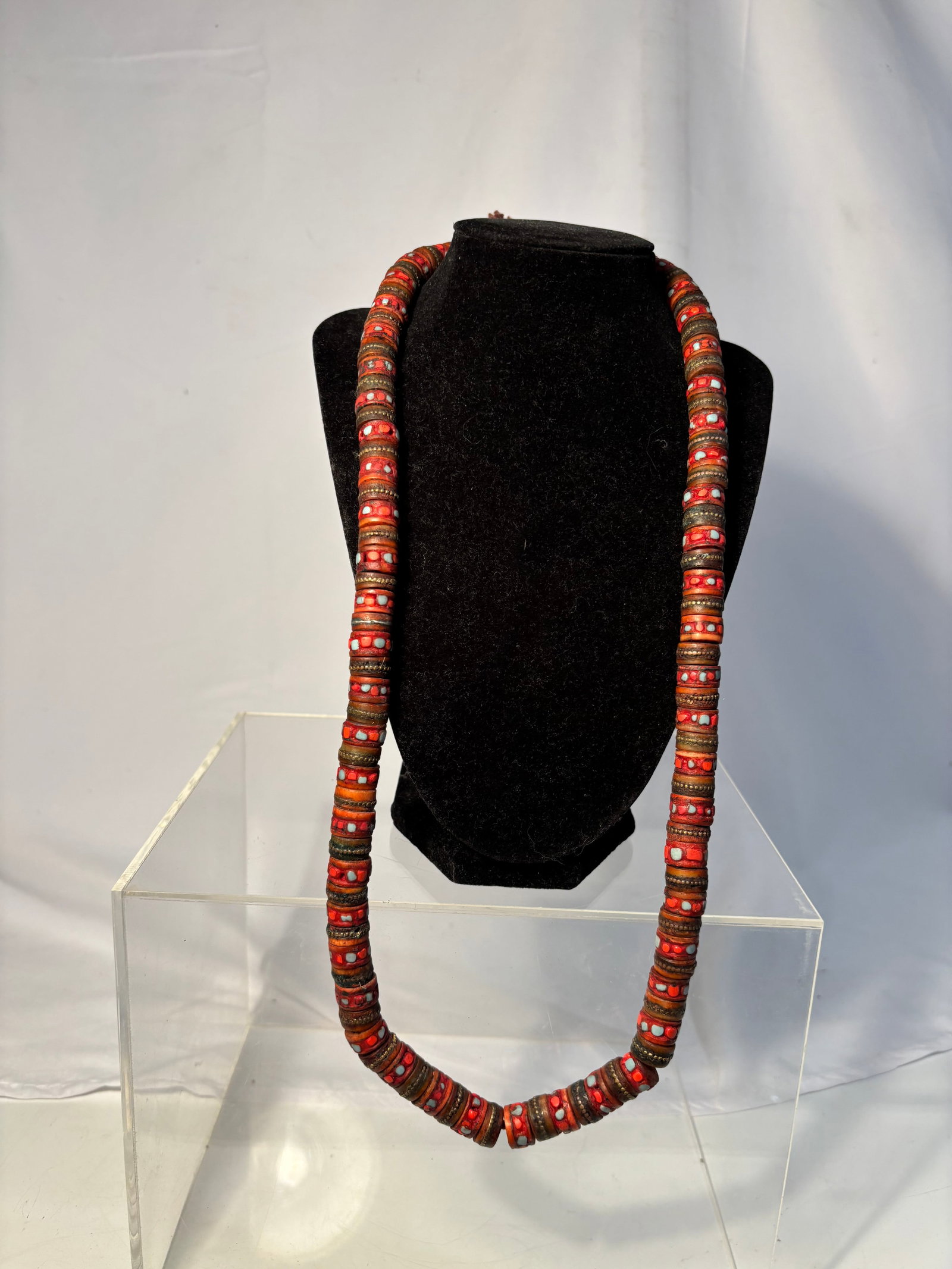 Vintage Tibetan Style Coral Colored Bead Necklace: A vintage Tibetan or Nepalese style necklace composed of coral-colored disc beads with white dot decoration and brass-tone spacers. Executed in an ethnic tribal taste with strong visual appeal and lay