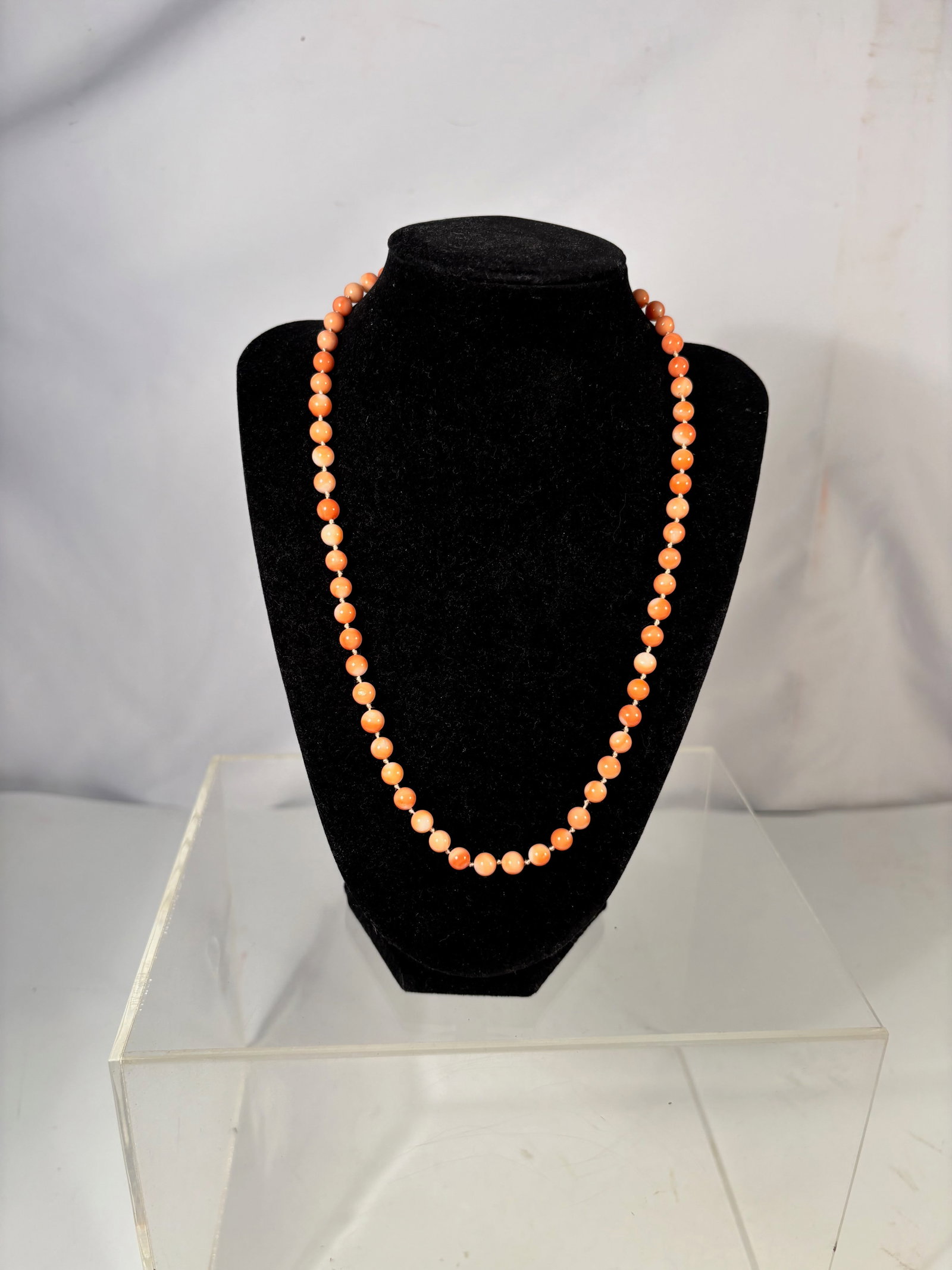 A Natural Coral Bead Necklace with 14K Gold Clasp: Necklace composed of small round natural coral beads in warm orange to salmon tones. The beads are strung in a graduated form and finished with a 14K gold clasp. Length: 20 inches.