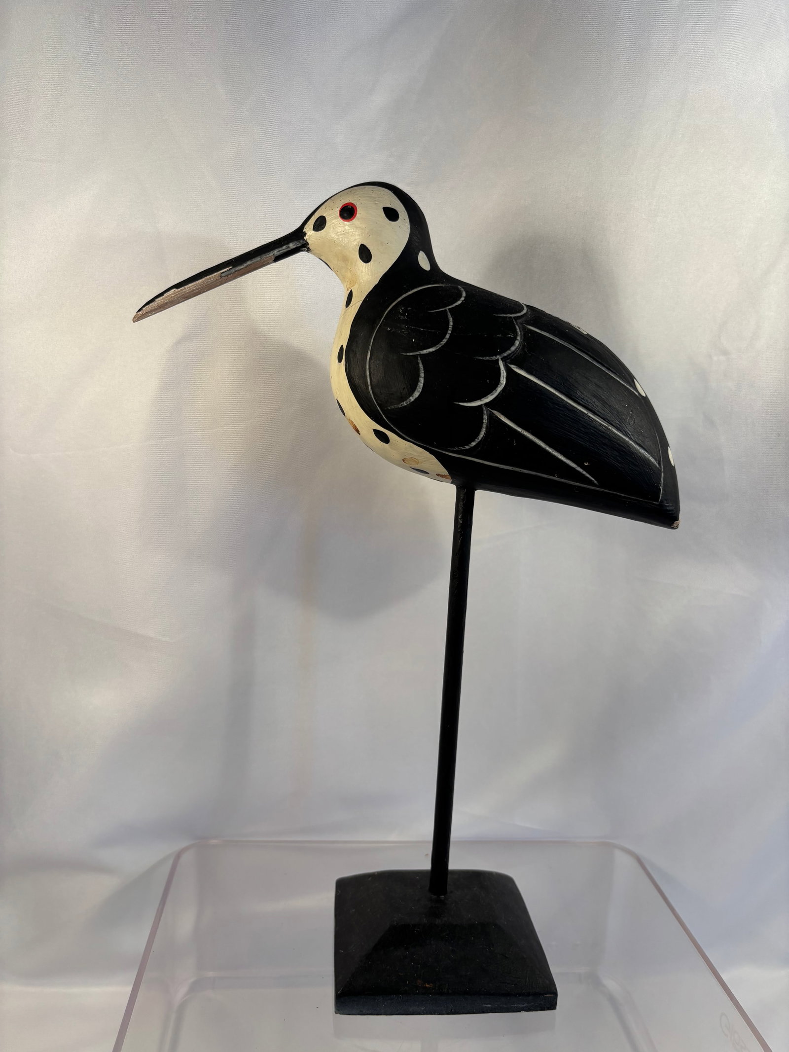 Vintage Folk Art Carved and Painted Spotted Shorebird Sculpture: A stylized folk-art shorebird carving featuring a long bill, cream-colored head and breast with black spotted decoration, black wings with incised feather details and red-rimmed inset eyes. Mounted on