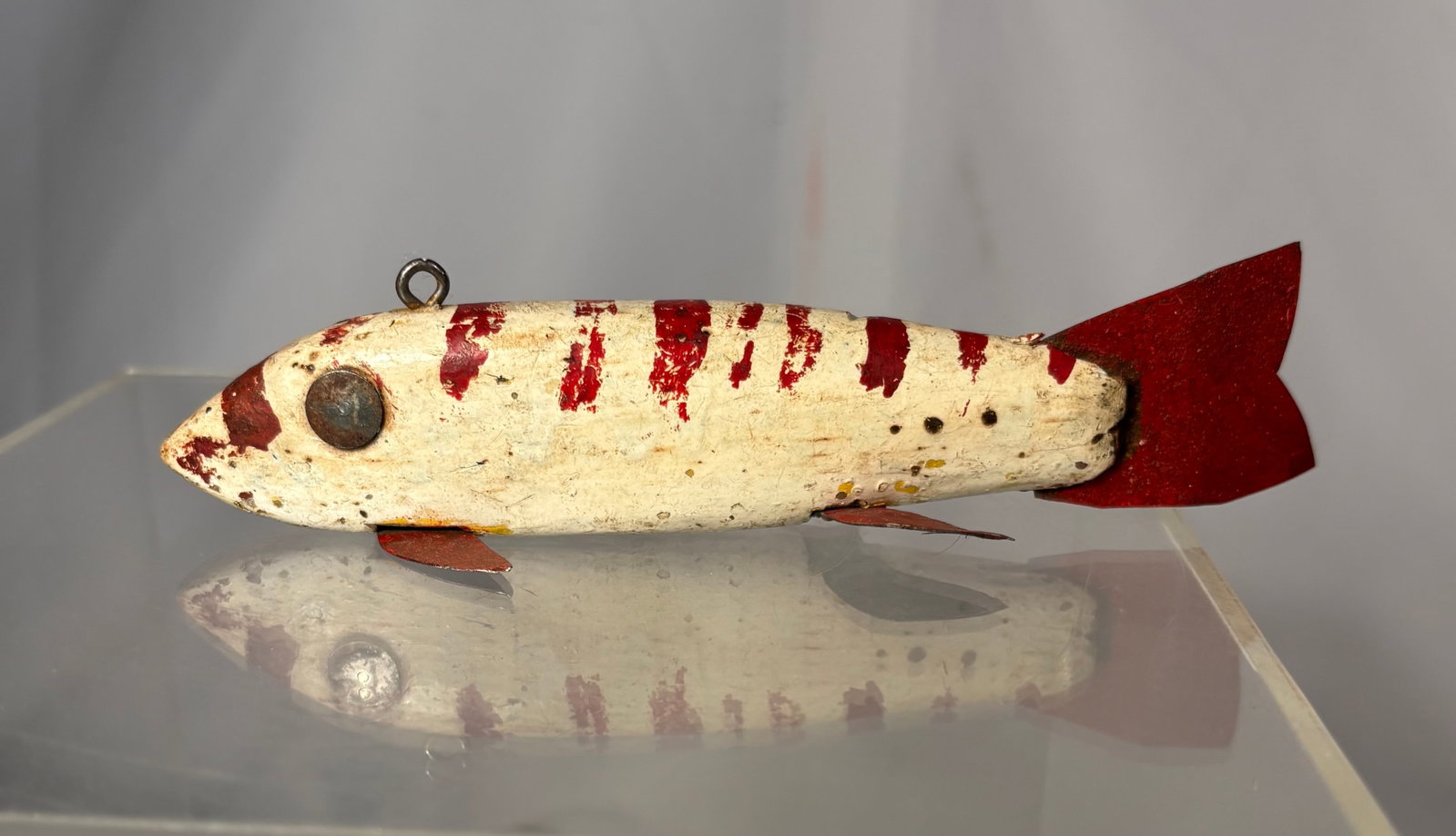 Antique American Folk Art Carved Wood Ice-Fishing Fish Decoy Early to Mid-20th Century, circa: An antique American folk-art ice-spearing fish decoy, hand-carved from wood and retaining distressed red-and-white painted decoration. Fitted with applied metal fins and tail, raised circular eyes, a 