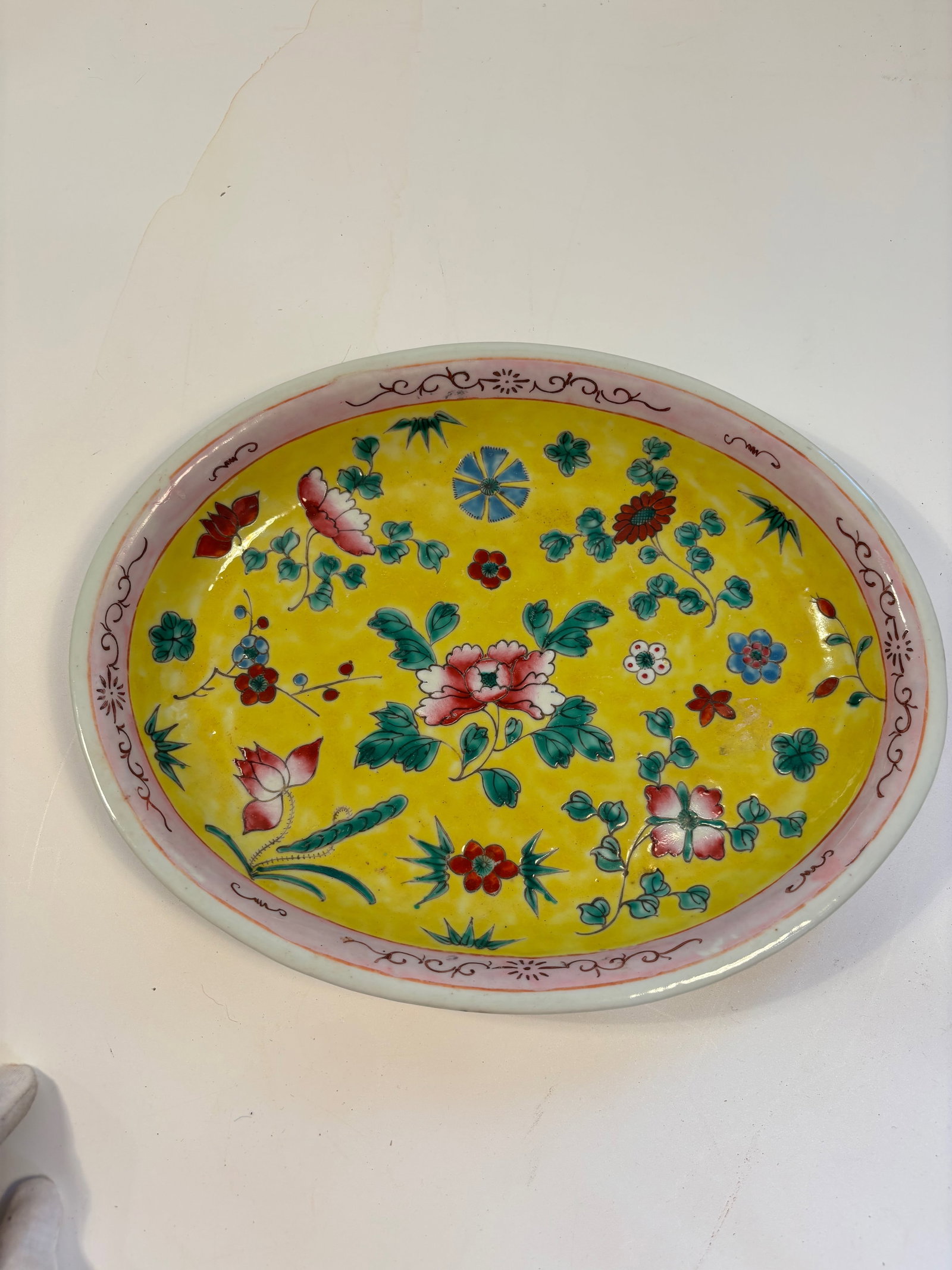 A Chinese famille rose porcelain charger: Late 19th to early 20th, A variation of the famille rose palette, where floral decorations are painted over a vibrant yellow glaze.Dimensions? Length: 12.5 inches ; Width: 9.5 inches; Height: 1.5 inch