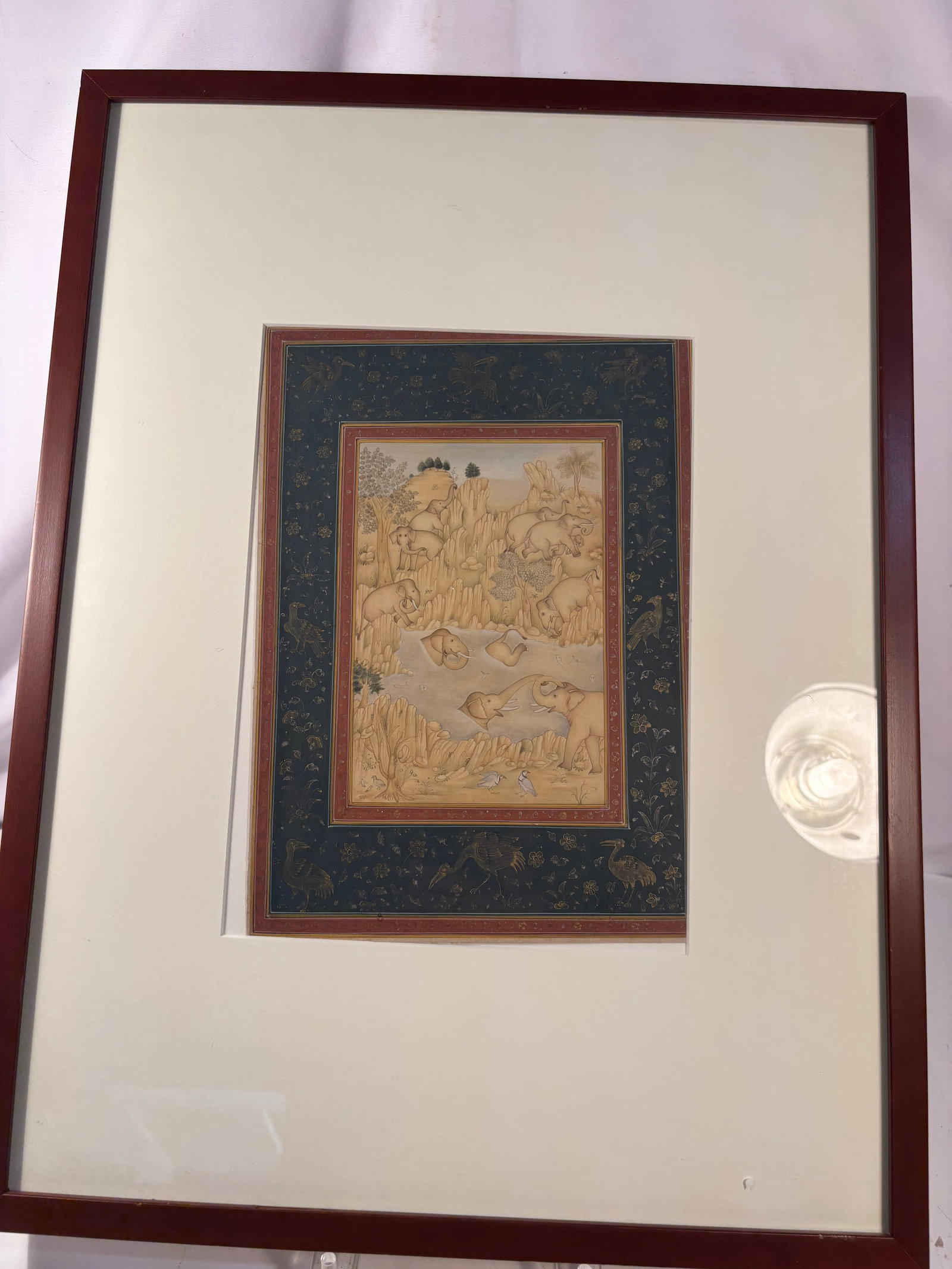 Hand-Painted Indian Rajasthani Miniature Painting of Elephants: A hand-painted Indian Rajasthani-style miniature depicting a herd of elephants roaming, bathing, and resting within a mountainous river landscape. Rendered in delicate earth tones with fine linework a