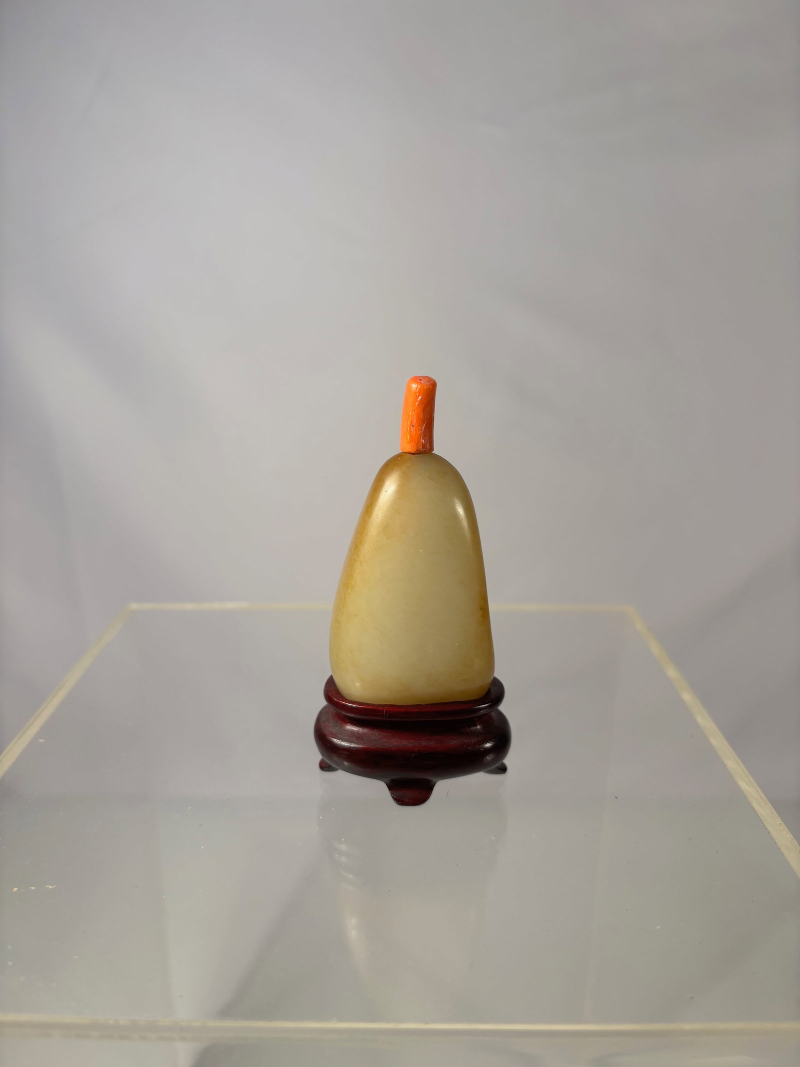 Chinese White Nephrite Jade Snuff Bottle with Natural Yellow Skin & Coral Stopper: Qing dynasty (1644-1912) ; A finely crafted Chinese snuff bottle made from high-quality white Hetian nephrite jade featuring a natural yellow skin .The bottle is smoothly polished in a rounded pebble 