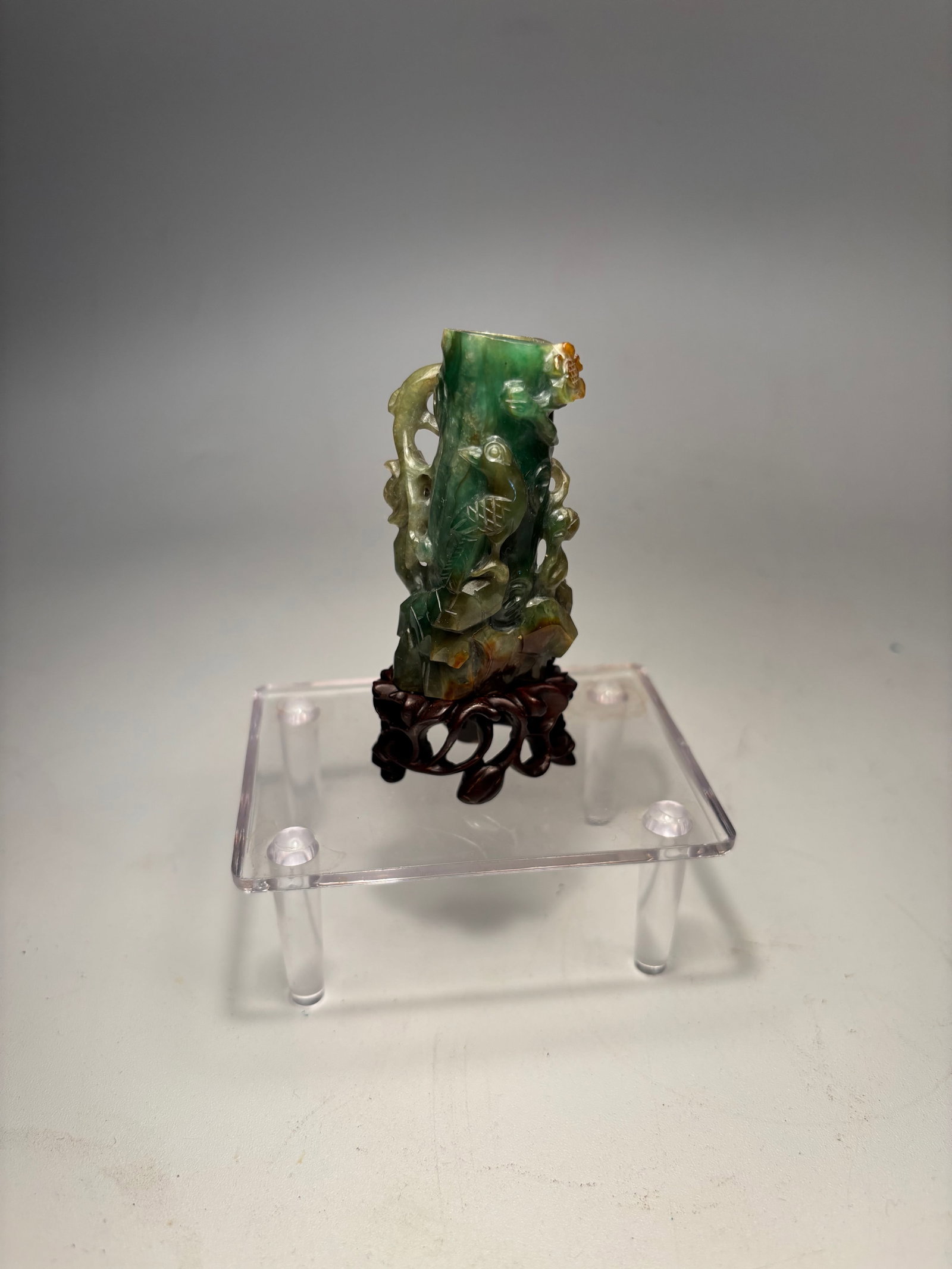 A Chinese hand carved jadeite scholar's Ornament wth stand: Qing dynasty(1644-1912); A finely carved Chinese jadeite scholar’s ornament, shaped as a vertical bamboo stalk rising from naturalistic rockwork, adorned with climbing lingzhi and floral vines. The 