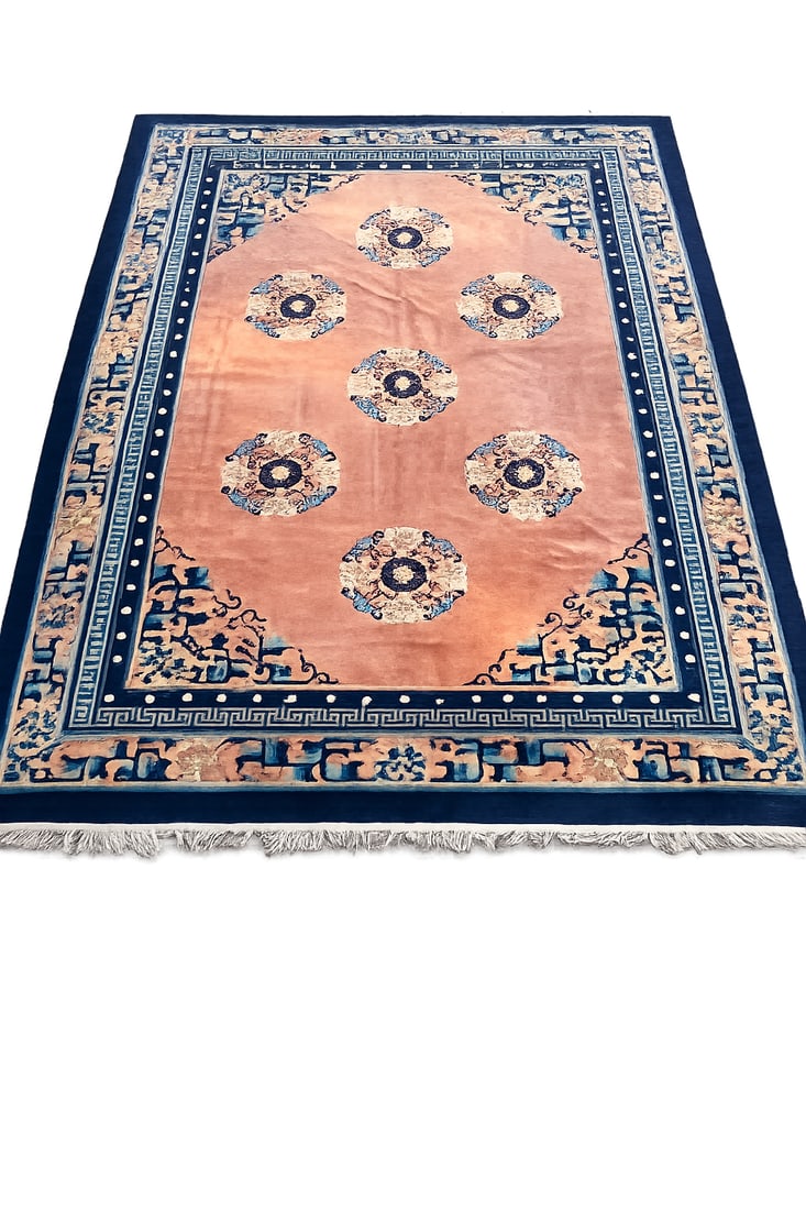 1920s Antique Chinese Peking Wool Rug with Seven Floral Medallions: An antique Chinese Peking hand-knotted wool rug dating to the 1920s, featuring a salmon-pink field decorated with seven circular floral medallions. The field is surrounded by geometric key-fret bands 