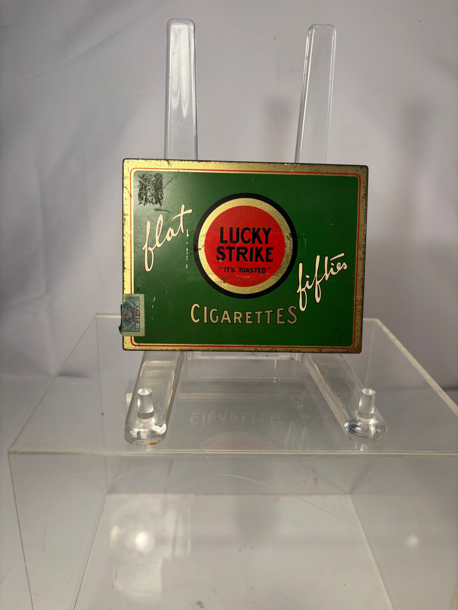 A Vintage Lucky Strike Metal Cigarette Case with Advertising Interior: Vintage metal cigarette case produced as an advertising or promotional item for Lucky Strike cigarettes. Rectangular hinged case with a gold-tone metal exterior. The interior lid is engraved with the
