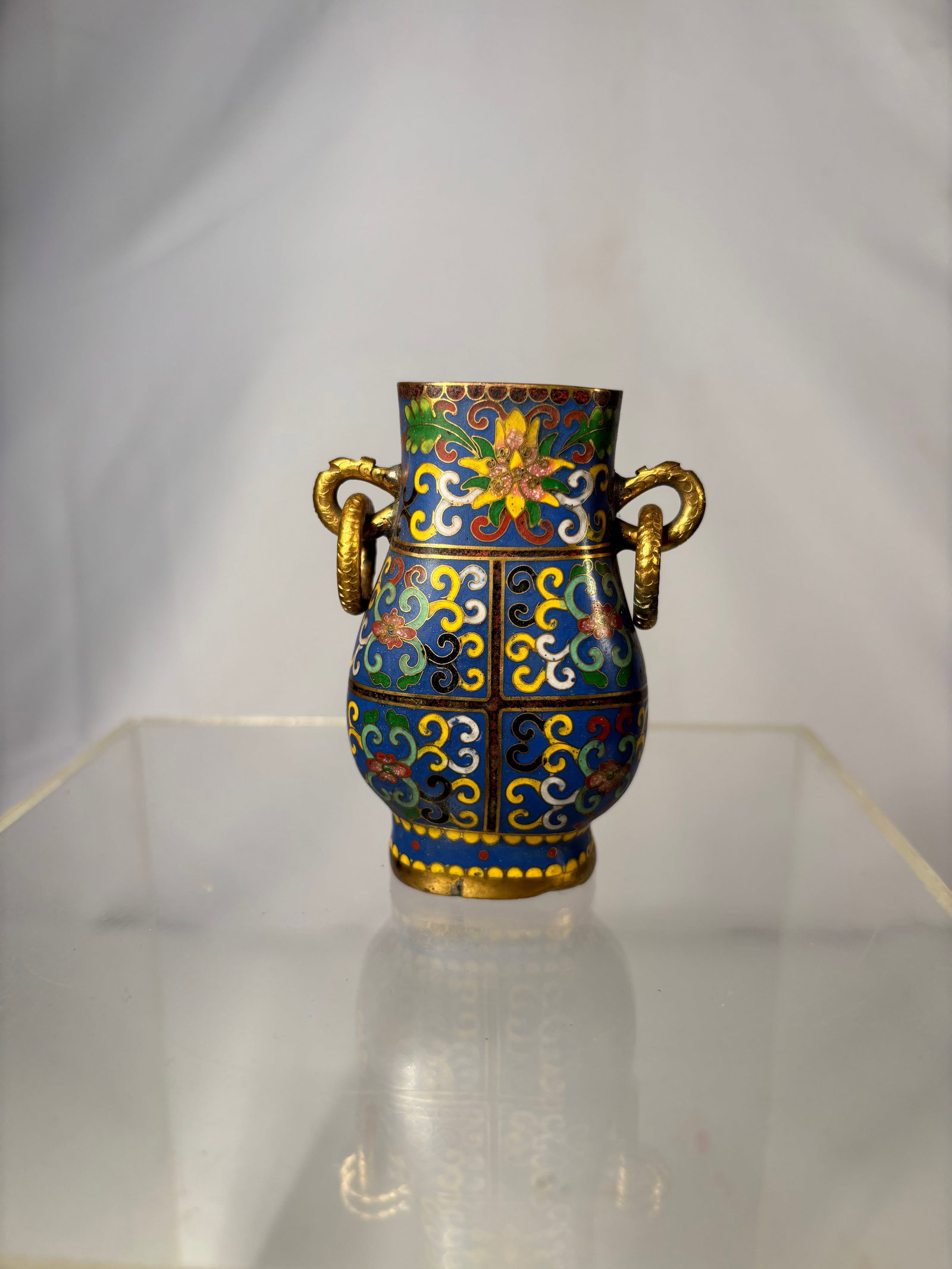 A Chinese Cloisonné Vessel with Gilt Ring Handles, 19th Century: Chinese cloisonné vessel of small baluster form, decorated with scrolling lotus and foliate motifs reserved on a deep cobalt-blue ground, executed in polychrome enamels of green, yellow, red, white, 