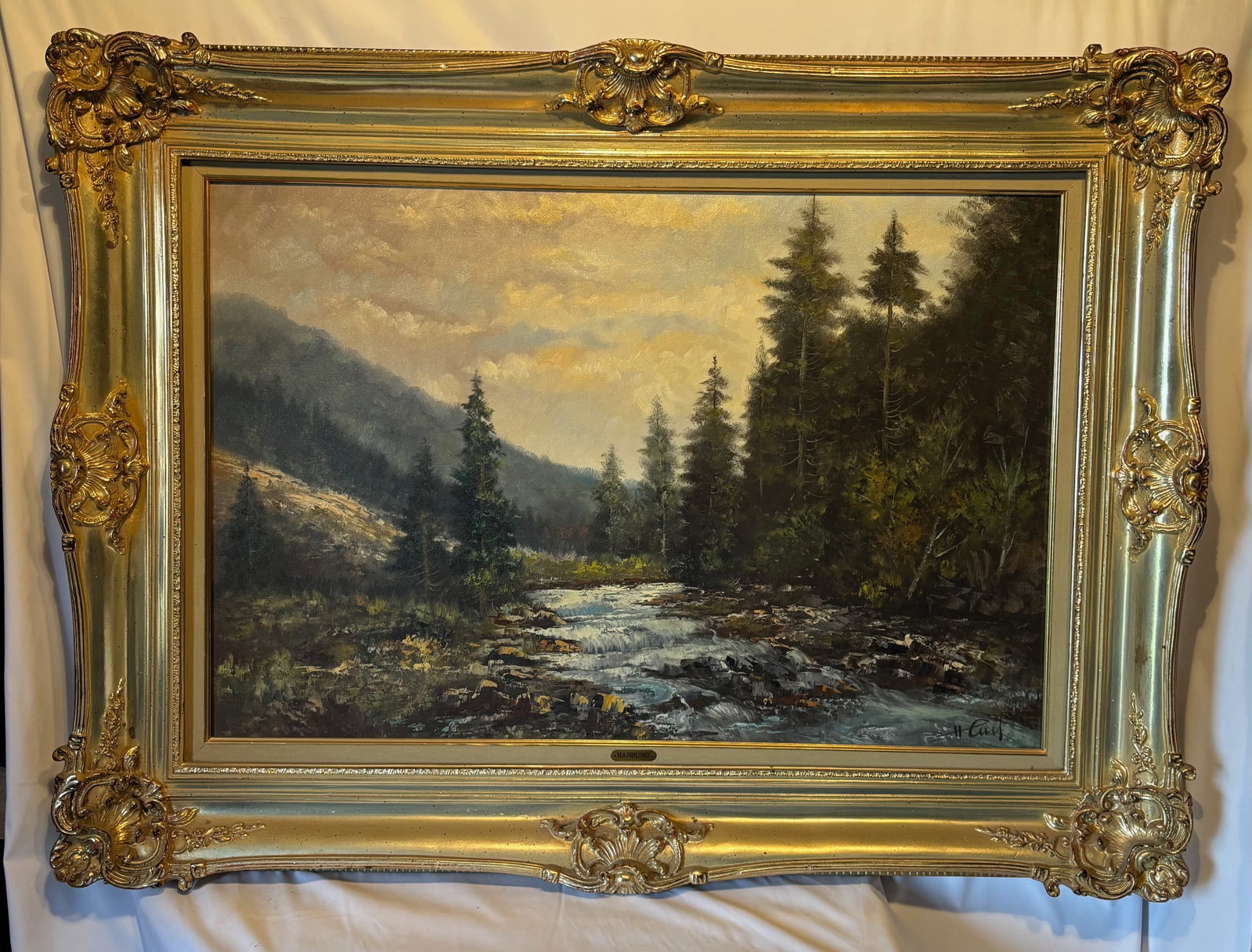 Large Framed Landscape Oil Painting Signed: Large oil on canvas landscape painting depicting a mountain stream flowing through a forested valley beneath a dramatic sky. Executed with expressive brushwork and palette knife texture, the compositi