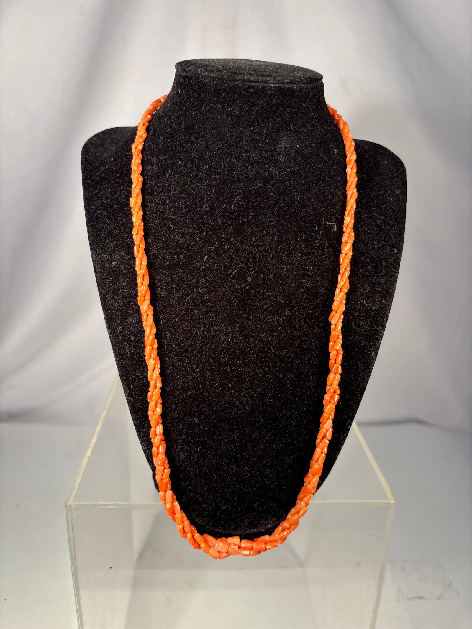 Vintage Multi-Strand Natural Coral Bead Necklace: A vintage necklace composed of multiple strands of small, irregularly shaped orange-red coral beads, arranged in a twisted rope-style design and finished with a gold-tone metal hook clasp. The natural