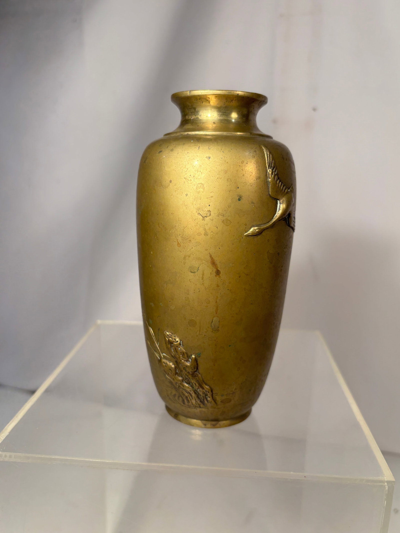 Japanese Meiji Mixed-Metal Bronze Vase with Crane and Frog, Circa 1890: A Japanese Meiji-period patinated bronze vase of elongated ovoid form with a flared mouth. Decorated in mixed-metal high relief with a flying crane to one side and a frog among aquatic grasses to the 