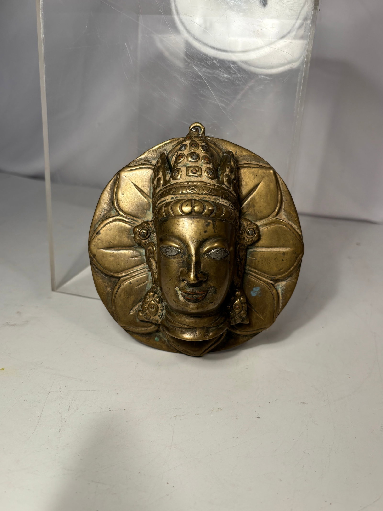 Antique Nepalese Brass Tara Mask Wall Plaque 19th century: An antique Nepalese cast-brass wall plaque depicting the crowned face of the Buddhist goddess Tara in high relief, surrounded by a stylized lotus-petal aureole. The elaborate five-point crown is decor