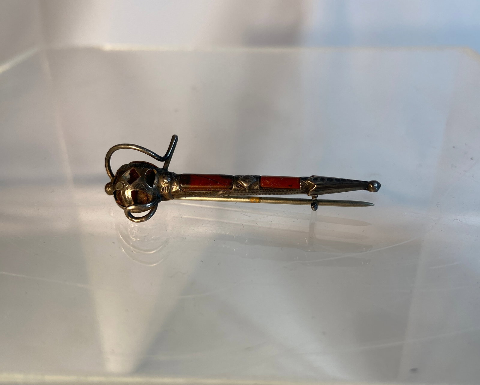 Vintage Sterling Silver Scottish Dirk Brooch with Colored Inlay: Vintage marked sterling silver Scottish dirk-form brooch featuring orange-colored inlay accents and an ornate basket hilt motif. The elongated dagger-form brooch is decorated with engraved detailing i