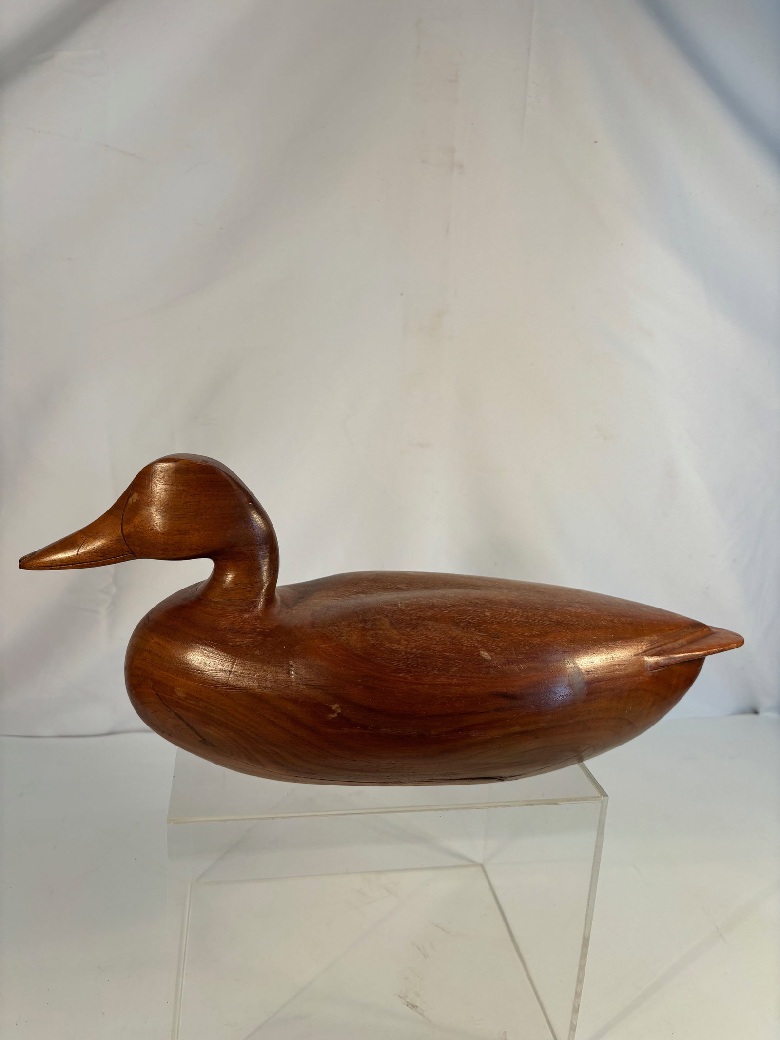 Heavy Hand-Carved Solid Wood Duck Decoy with Natural Finish: A finely hand-carved solid wood duck decoy, the streamlined form skillfully shaped with subtle contours and a polished natural finish emphasizing the grain of the wood. The underside with a single dri