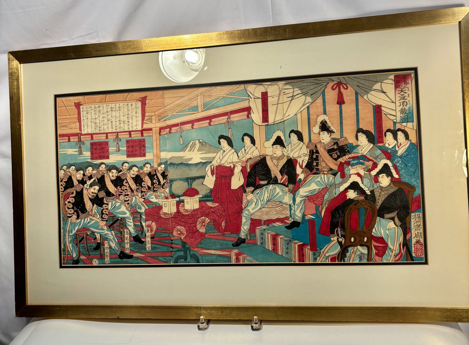 Large Meiji-Era Diplomatic Banquet Scene – Woodblock Print by Yosh? Chikanobu (Toyohara: A vibrant Meiji-period woodblock print depicting a grand diplomatic reception inside an ornately decorated hall. Seated officers in Western military dress face a group of court ladies in elegant kimon
