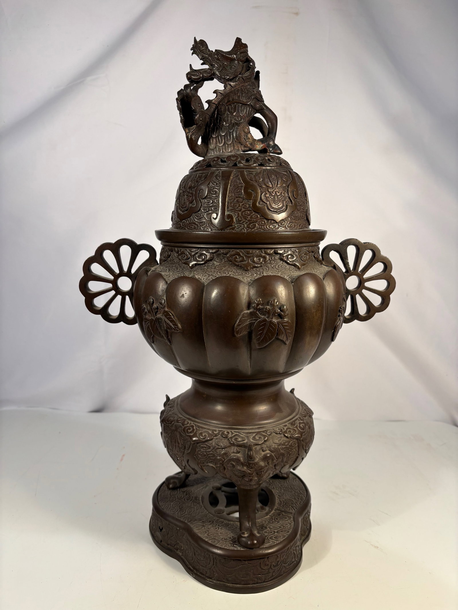 A Large Japanese Bronze Censer with Dragon-Form Finial: Meiji period (1868–1912), Japanese bronze censer (k?ro), of baluster form with a lobed body cast in relief with floral and foliate motifs. The censer is fitted with pierced openwork handles and a do