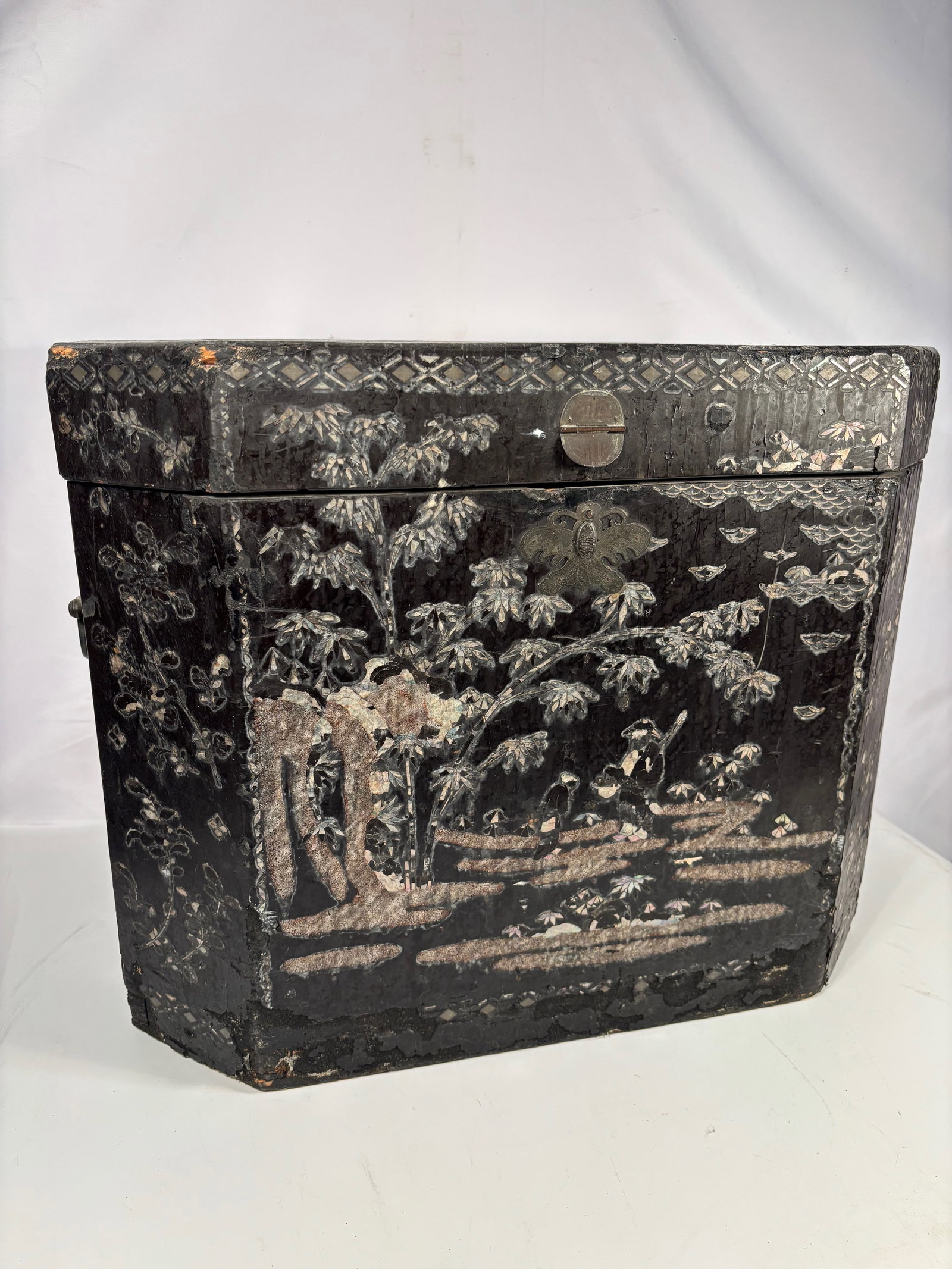 A Large Chinese Carved Lacquer Faceted Box with Mother-of-Pearl Inlay, Late Ming–Early Qing dyasty: 16th-17th century; Of faceted form, the box carved through multiple layers of dark lacquer to depict continuous landscape and floral scenes, incorporating trees, foliage, rocks, and ground lines in lo