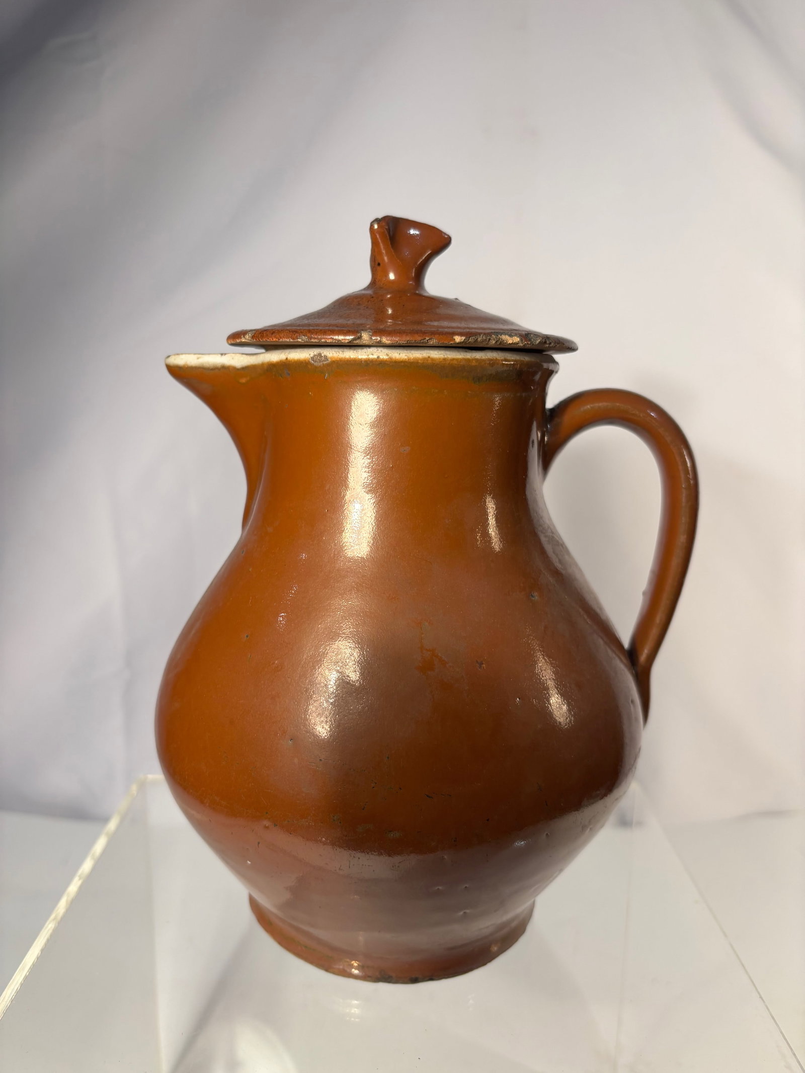 Rustic Old Brown-Glazed Stoneware Pitcher – Antique Farmhouse Primitive Water Jug, 19th Century: A hand-thrown rustic brown-glazed stoneware pitcher with flared spout, rounded body, and sturdy loop handle, covered in a glossy iron-rich glaze that transitions from deep chestnut to warm amber tones