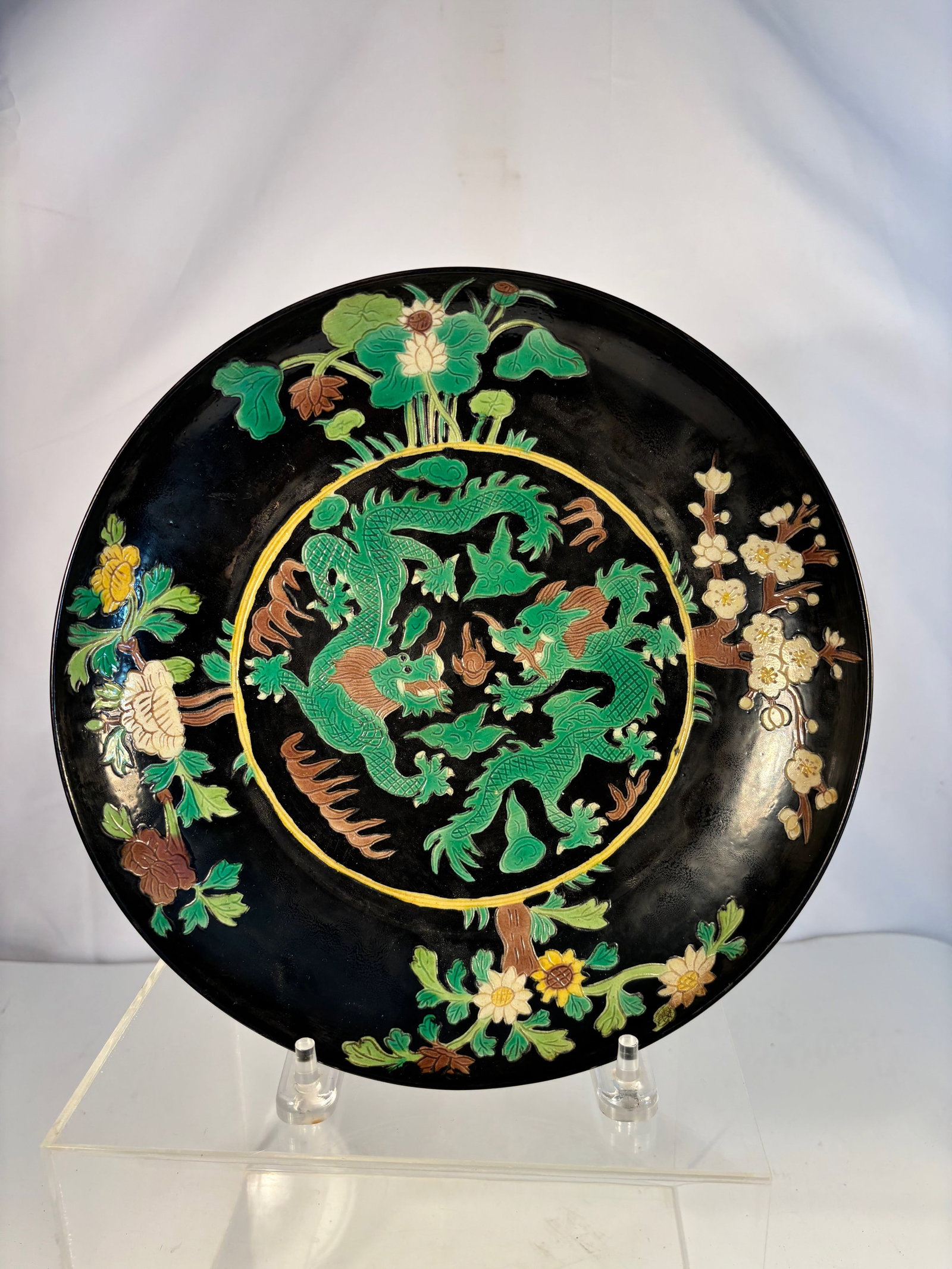 Chinese Black-Ground Porcelain Dish with Molded Dragon and Floral Design, Kangxi Mark,: Qing Dynasty(1644-1912);Of circular form with gently flared rim, the surface decorated in vivid green, turquoise, yellow, and aubergine enamels depicting a sinuous dragon amidst scrolling clouds and f