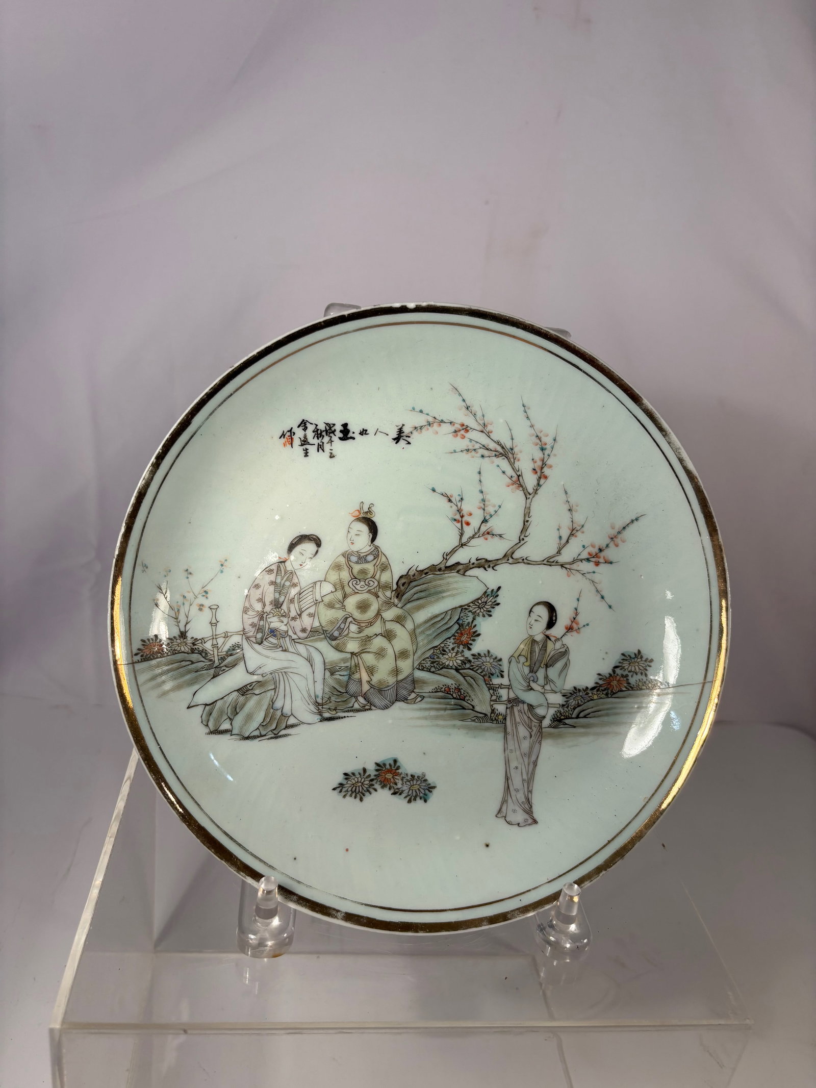 A Chinese Famille-Rose Porcelain Plate: Qing dynasty(1644-1912); A finely painted Chinese famille-rose porcelain plate, depicting elegant court ladies in a garden scene.Two seated ladies are shown conversing on rockwork beneath a blossoming