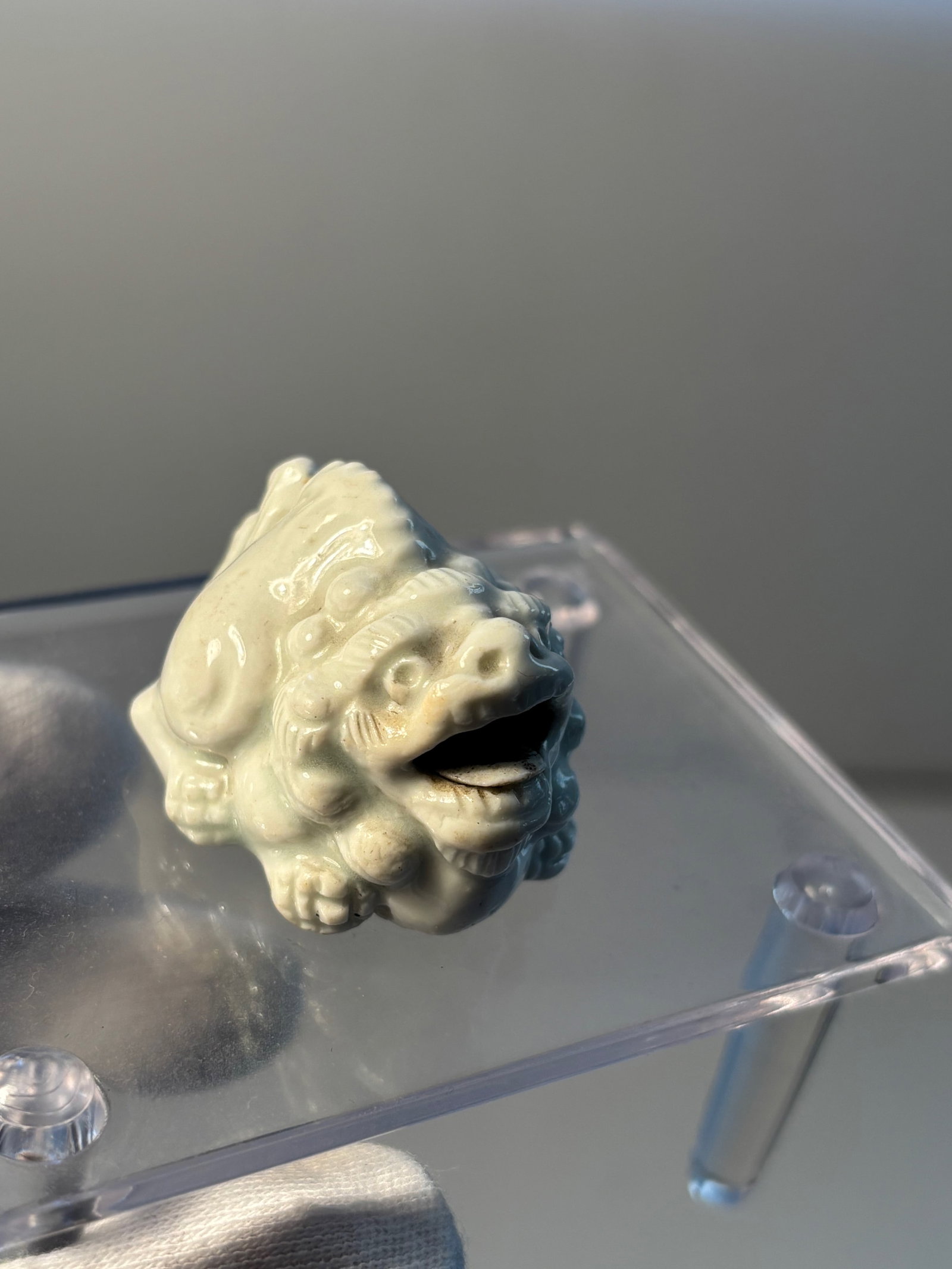 A Hirado porcelain netsuke of a shishi: 19th century; The white-glazed pottery lion dog seated, facing ahead, its head raised and its open mouth containing a loose ball, unsigned.The property of a Private Collector. Dimensions? 4.2cm (1 5/8