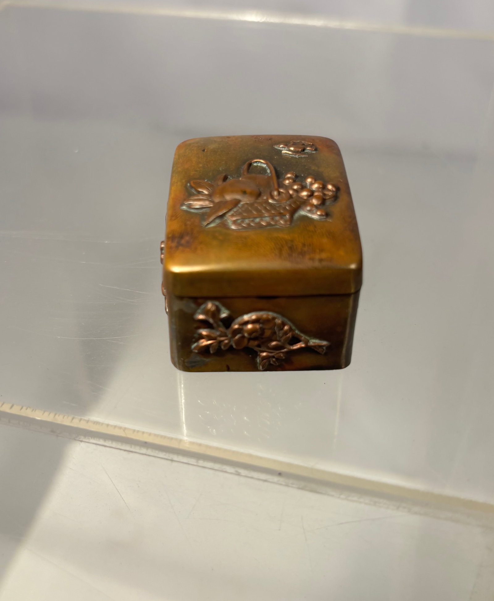 Meiji Period Japanese Mixed-Metal Hinged Pocket Box with Floral and Fruit Motifs: A Japanese Meiji-period mixed-metal pocket box of rectangular form, constructed in brass/bronze and decorated with applied relief motifs of flowers, fruit, leaves and baskets in contrasting metals. Fi