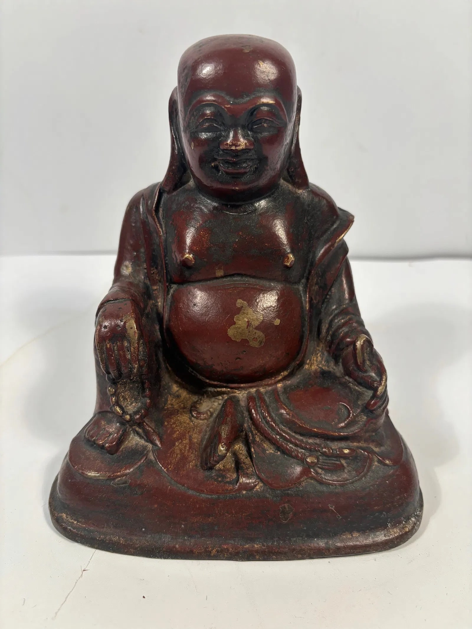 A Chinese gilted and red lacquered bronze Happy buddha Statue: Qing Dynasty (1644-1912), Traces of gold leaf or paint are still visible, particularly on the belly and garments; Dimensions?Height: 7 inches .