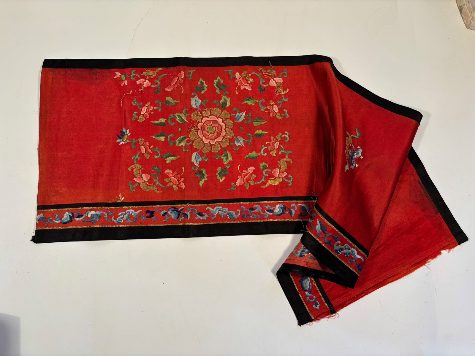 A Chinese red silk embroidered ceremonial panel: 19th century;Central Floral Medallion: The embroidered roundel at the center features lotus or peony blossoms surrounded by vines and smaller flowers. Dimensions?Length: 35 inches ; Width: 10.5 inches