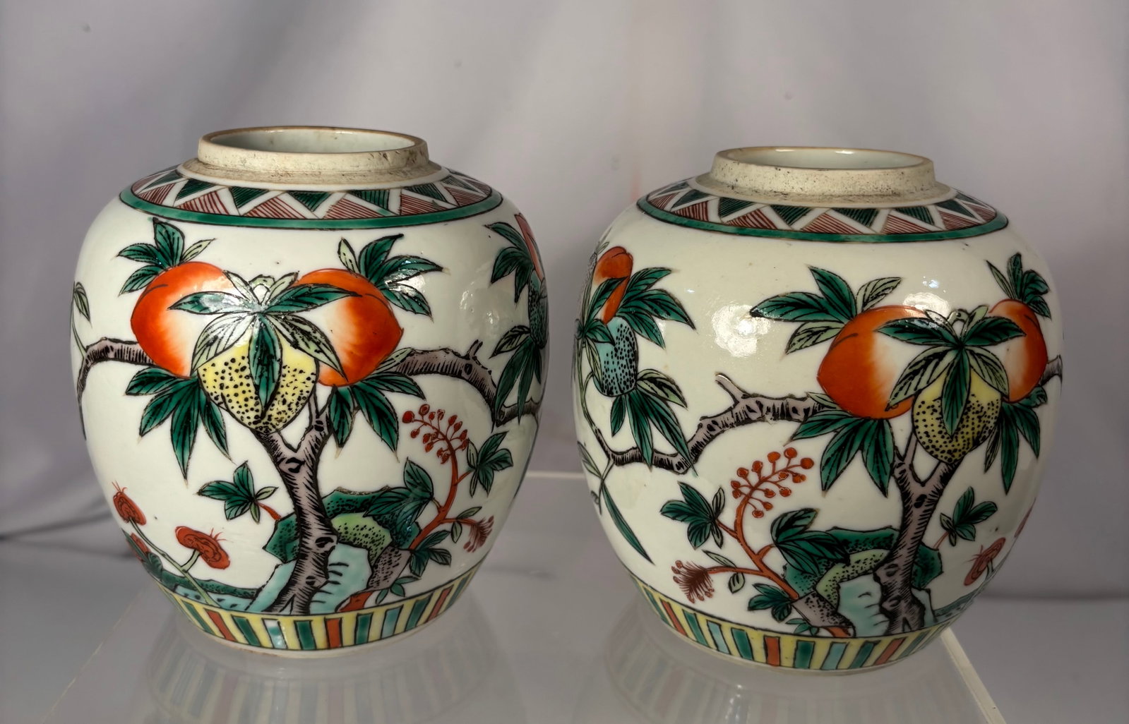 Pair of Chinese Ginger Jars with Peach & Bird Decoration 19th century: A matched pair of cream-ground ceramic ginger jars, ovoid form with short cylindrical necks. Each is hand-painted with a branch of ripening peaches (a traditional Chinese symbol of longevity) in orang
