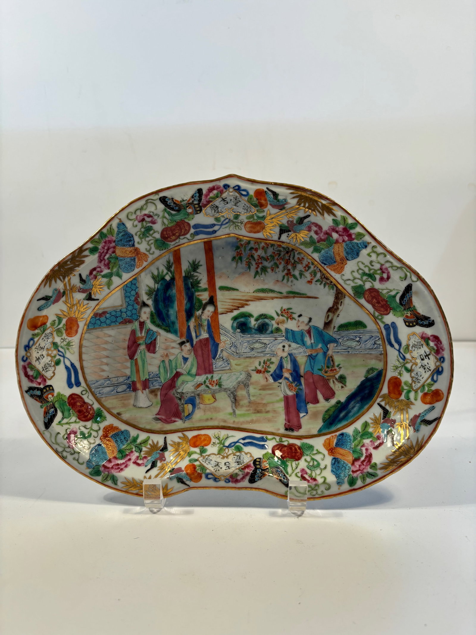 A Chinese famille rose porcelain scalloped shape platter: Qing Dynasty (1644-1912), It features a traditional Chinese garden scence of several people , which might represnet a legendary tales or historical scenes.Dimensions? Length: 11.25inches ; Width: 8.5i