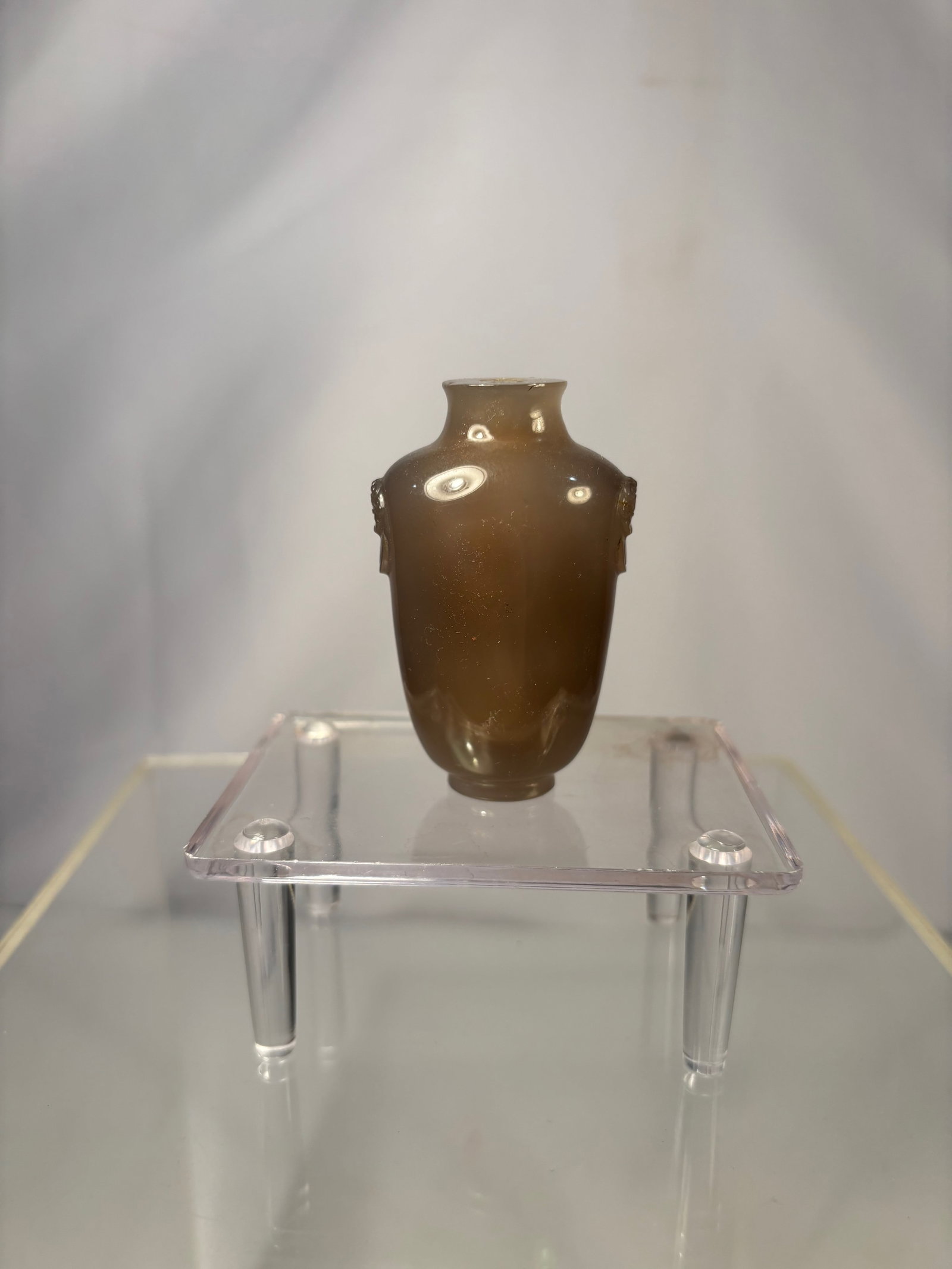 A Chinese Agate Snuff Bottle with Mask Handles: Qing dynasty(1644-1912); Chinese snuff bottle carved from agate, of ovoid vase form with a short waisted neck and recessed foot. The shoulders are applied with small animal-mask handles, and the body