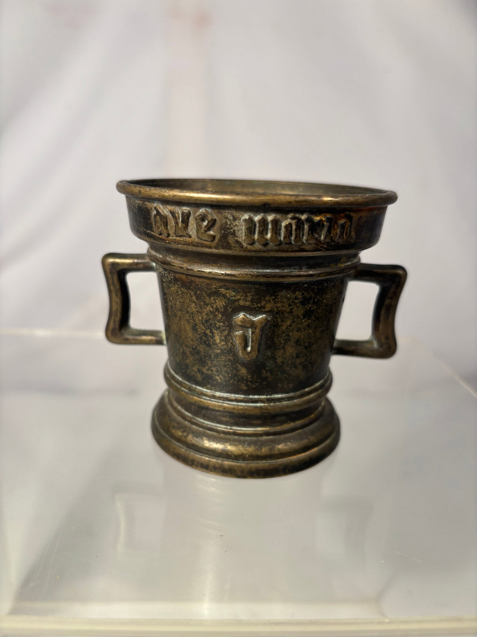 European Gothic Revival Bronze Mortar with “Ave Maria?? Inscription 18-19th century or early: A heavy cast-bronze apothecary mortar of cylindrical form, fitted with two rectangular side handles and a broad molded foot. The upper register bears a raised Gothic-style inscription appearing to rea