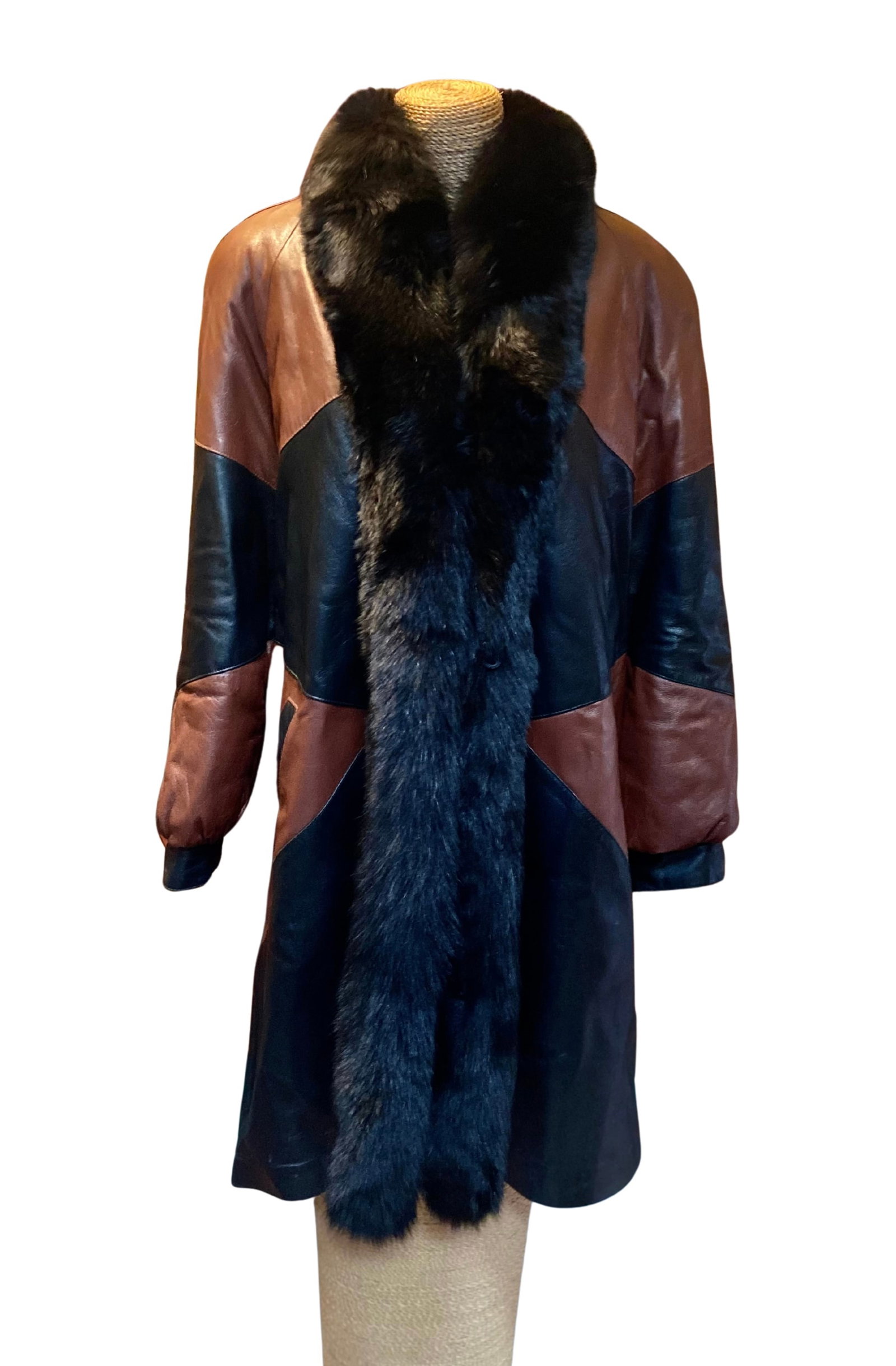A Color-Block Leather Coat with Fur Trim: A leather coat featuring a striking color-block design in brown and black leather, accented with a plush fur-trimmed collar and full-length fur trim at the front. The coat is tailored in a straight