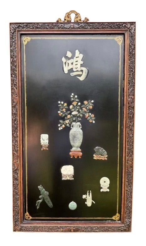 A Large Chinese Jade-Inlaid Wall Panel with Floral and Symbolic Motifs: Qing Dynasty(1644-1912)A large Chinese wall panel featuring multiple inlaid jade carvings set against a black lacquer ground. At the center is a vase with blooming flowers, surrounded by auspicious ja
