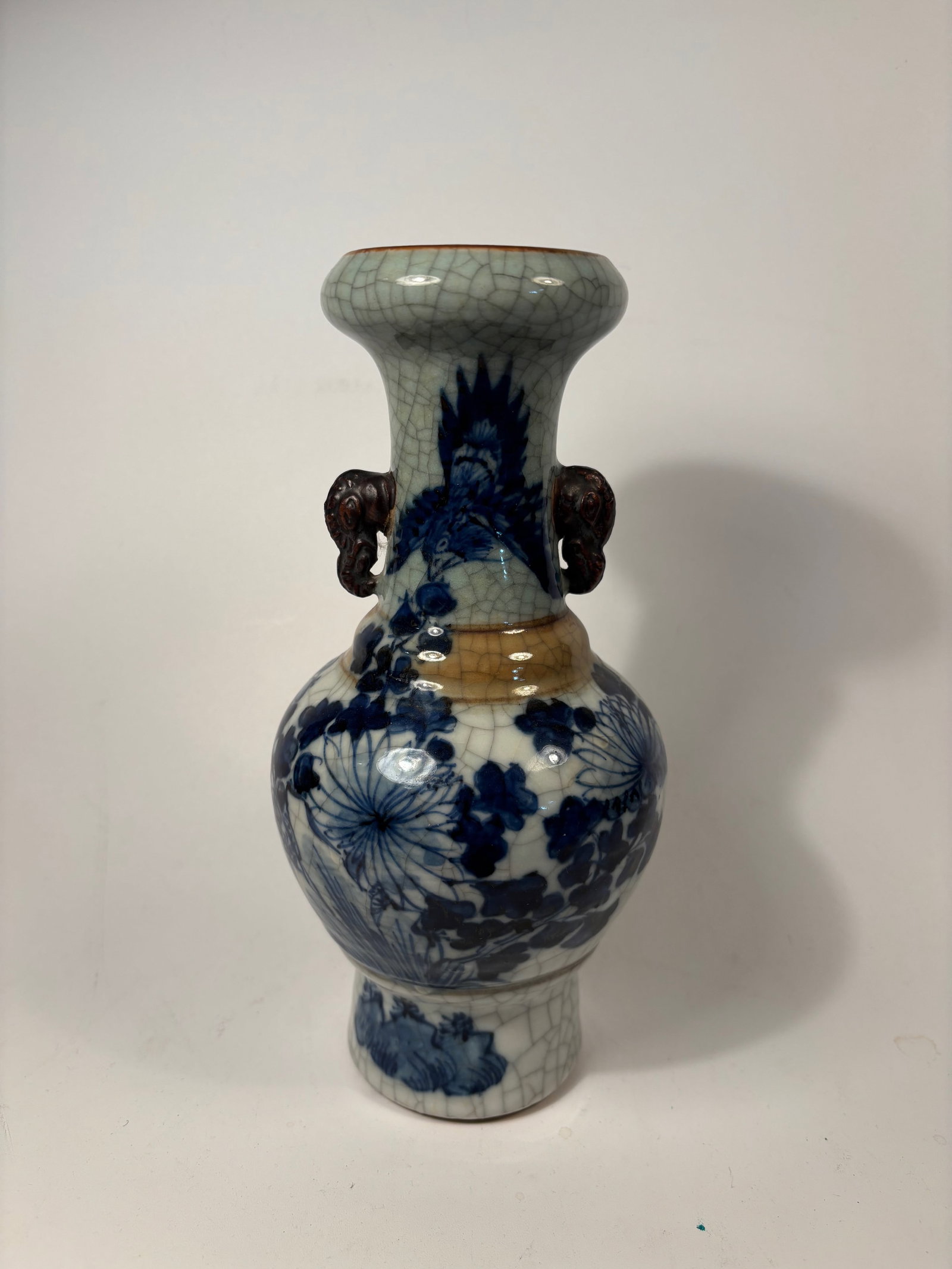 A Chinese crackle-glazed vase with underglaze blue floral decoration: Qing dynasty(1644-1912); Feels very heavy on hand; Chinese crackle-glazed vase with underglaze blue floral decoration and applied animal head handles; Dimensions?Height: 9 inches.