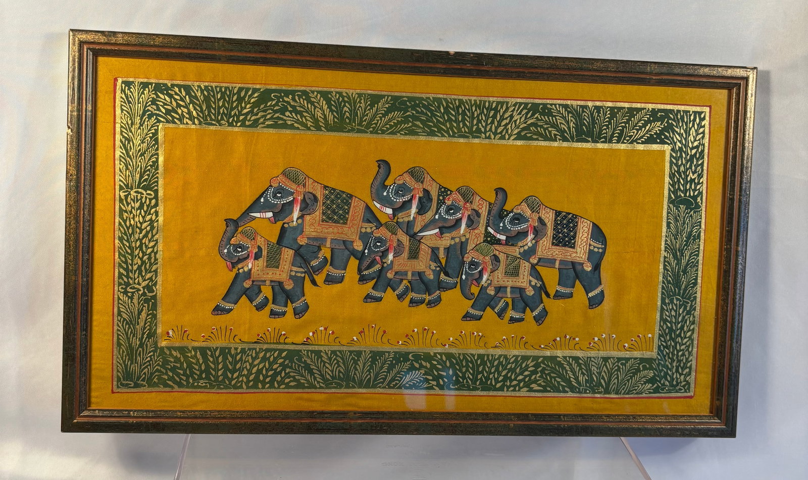 Indian School, Decorated Elephant Procession Painting: A vintage Indian-style painting on fabric depicting a ceremonial procession of seven richly decorated elephants against a golden-yellow ground. Detailed with colorful saddle cloths, jewelry, and ornam