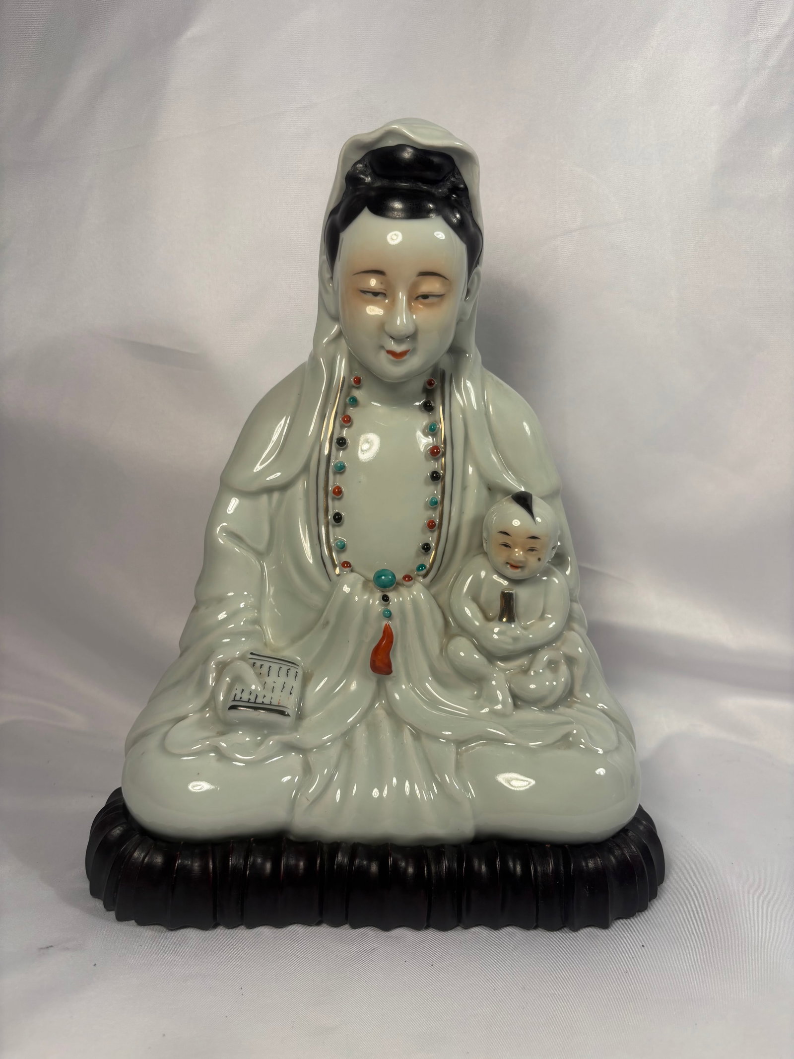 Chinese Enameled Porcelain Songzi Guanyin and Child Figure, “Mao Ji Sheng Zao?? Mark, late 19th: A Chinese enameled porcelain figure depicting Songzi Guanyin, the Bodhisattva of Compassion, seated in flowing robes with a smiling child nestled at her side. Guanyin holds an inscribed scripture tabl
