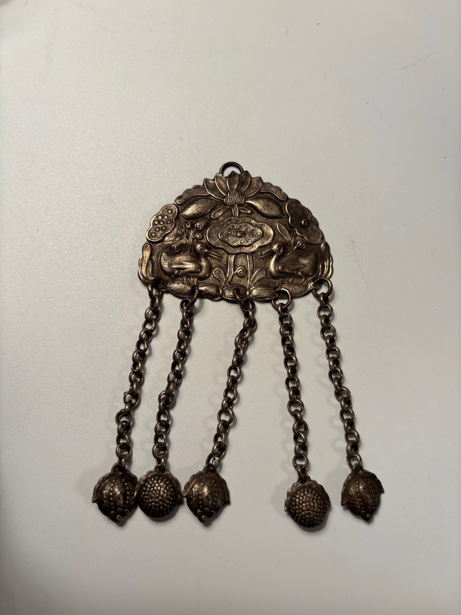 A Chinese Silver Pendant with Lotus and Frogs,: Qing dynasty(1644-1912); A Chinese silver pendant ornament, late Qing period, finely cast and chased in relief with lotus flowers flanked by a pair of frogs among foliage, symbolizing fertility and ab