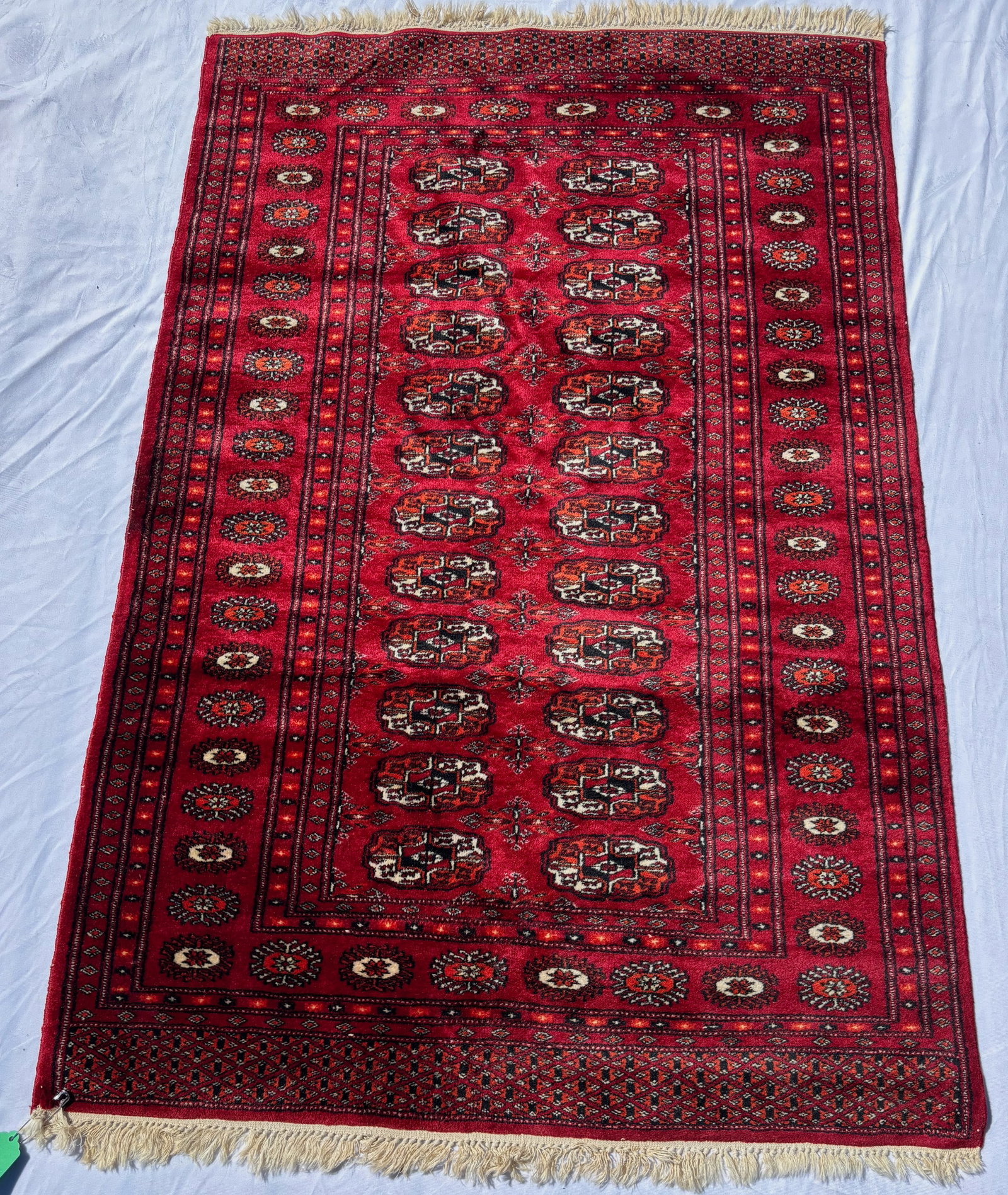 Fine Hand Knotted Pakistani Bokhara Silky Wool Rug, 60 x 38 in.: A finely hand knotted Pakistani Bokhara style rug featuring repeating gul medallions on a rich crimson field with intricate geometric borders. Woven with silky wool pile exhibiting a soft luminous she