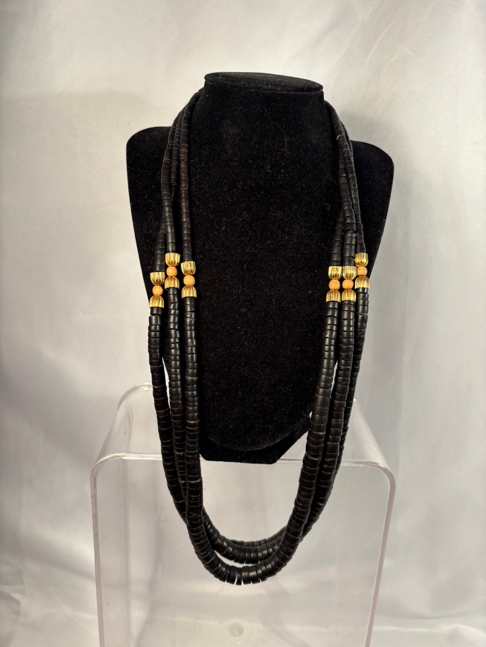 Vintage Multi-Strand Black Coconut-Shell and Wood Bead Necklace: A vintage statement necklace composed of multiple strands of black coconut-shell disc beads, accented at intervals with fluted gold-tone metal beads and rounded natural wood spacers. The numerous grad