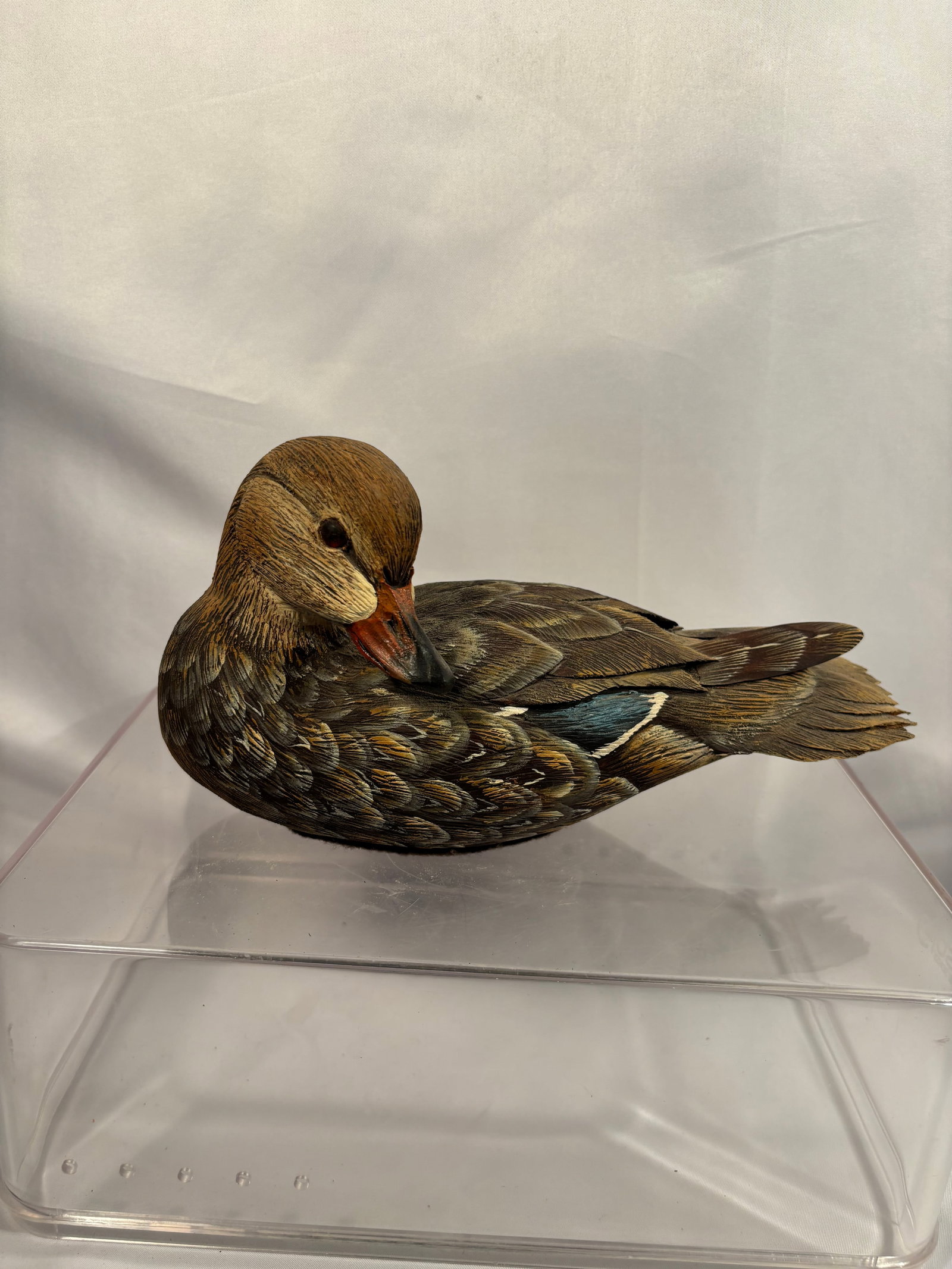 Charles Burns Signed Hand-Carved Wood Duck Hen, 1997: A finely detailed, hand-carved and hand-painted wooden sculpture by Charles “Charlie” Burns, depicting a female wood duck in a resting pose with its head turned toward its back. The carving fe