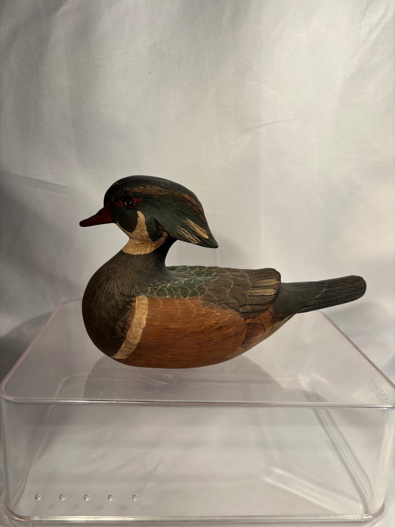 L. Everhart Signed Hand-Carved Wood Duck Drake, Dated 1984: A hand-carved and hand-painted wooden sculpture by L. Everhart, depicting a male wood duck in a distinctive resting pose with its crested head turned backward. The carving features deeply incised feat