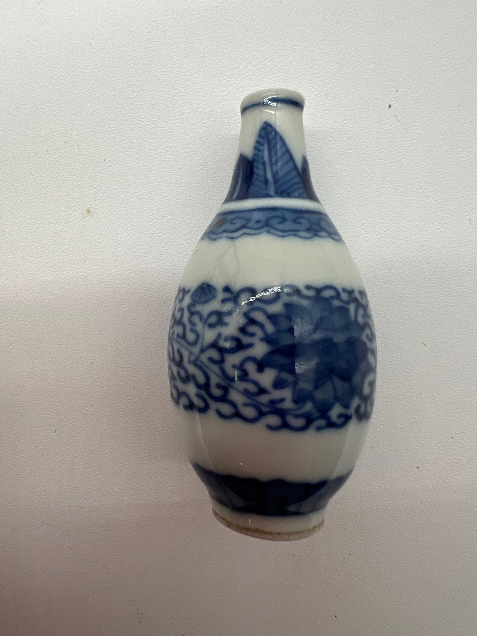 A Chinese blue and white porcelain hand painted snuff bottle: Qing Dynasty (1644-1912); This piece features intricate, repeating patterns in blue, including a central band that seems to show swirling clouds or abstract motifs, along with additional decorative el