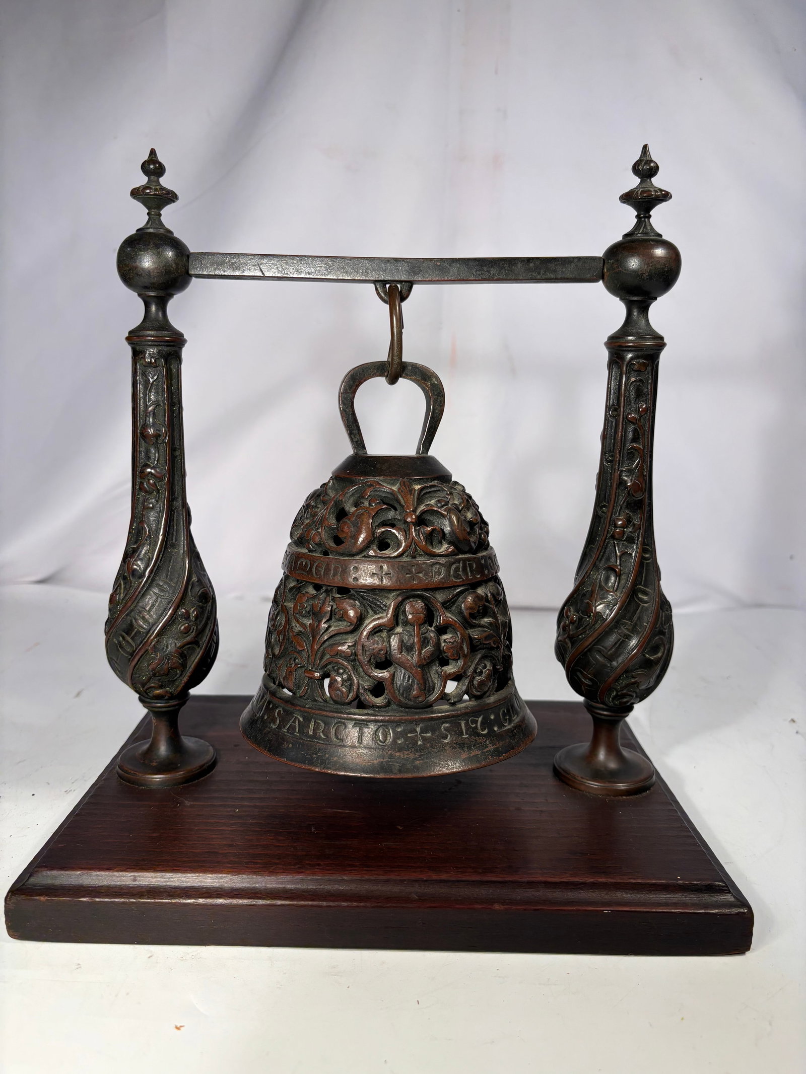 Vintage European Bronz Bell with Latin Inscriptions on Display Stand 18-19th century: The bell is richly decorated with pierced openwork foliate scrolls, religious figures and Latin inscriptions naming the Evangelists around the body. Retains an interior bronze clapper and is suspended