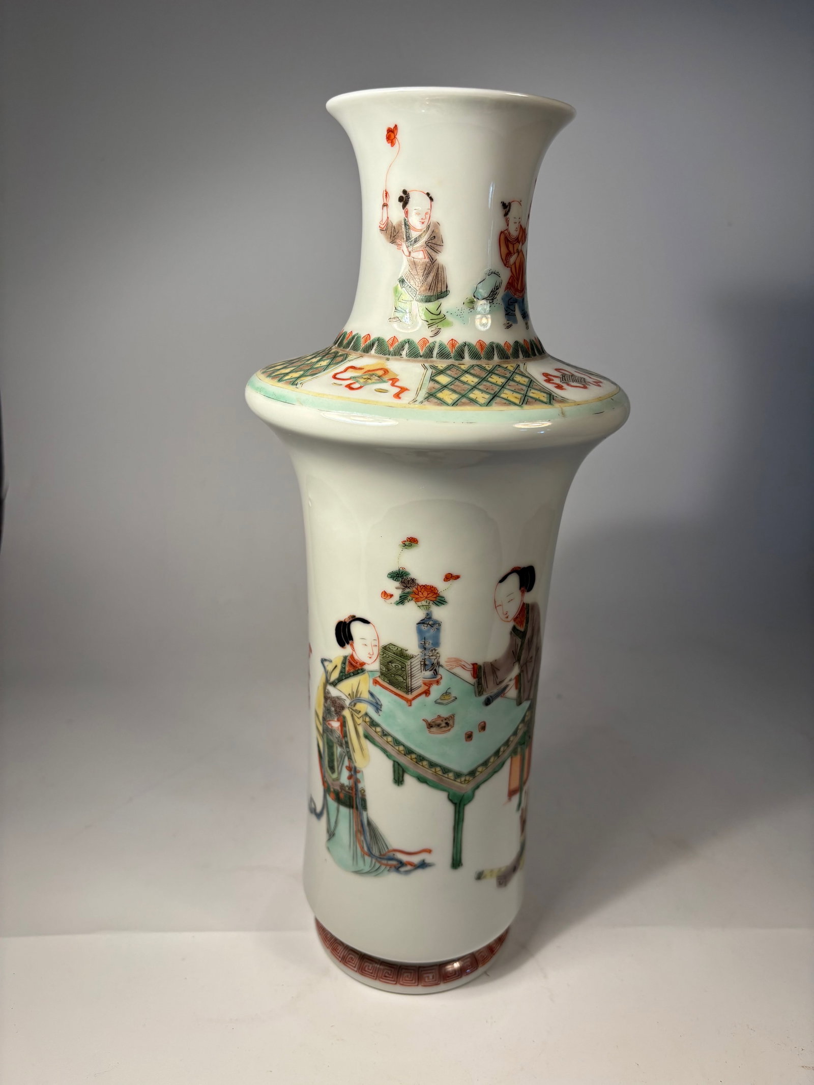 A Chinese famille rose porcelain vase: Qing dynasty(1644-1912); Gu-form (beaker-style) vase with flared rim and mid-waist flange; Hand-painted with figural scenes, possibly scholars or court ladies, in a garden or interior setting;Fine fam
