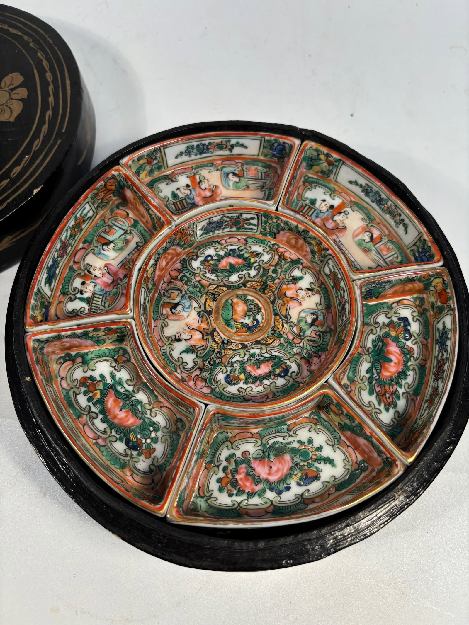 A Chinese Gilt Lacquered Wood Cosmetic Box with Porcelain sets Inserts: Qing Dynasty(1644-1912);A Chinese circular lacquered wood box with a fitted lid, decorated in gilt with a finely rendered peacock perched among plum blossoms, bordered by a wave-scroll pattern. The bo