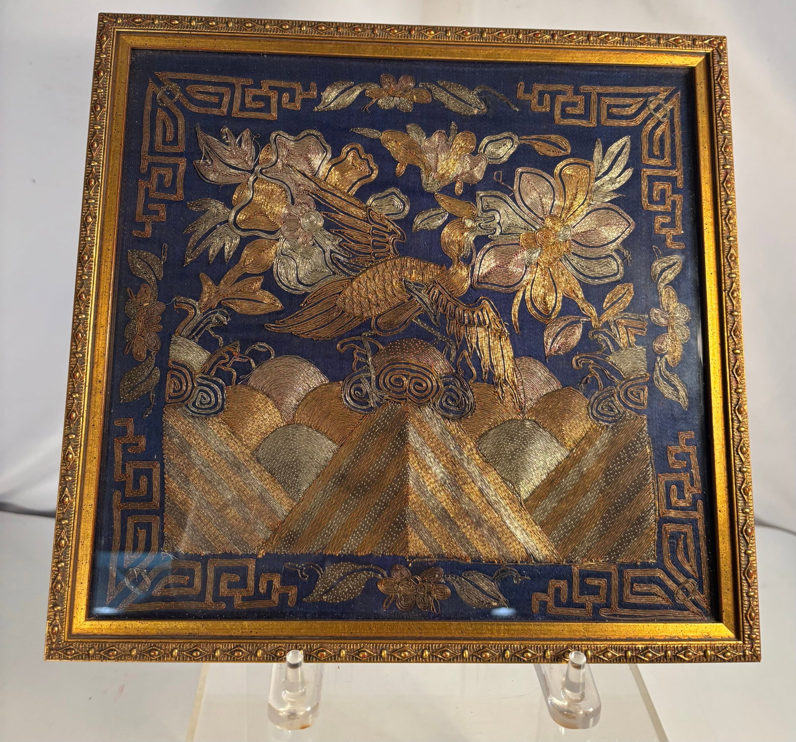 Chinese Qing Dynasty Embroidered Mandarin Square Rank Badge: The square embroidery features a central bird, possibly an egret or golden pheasant, perched on stylized rocks above waves.The artwork utilizes metallic gold and silver threads alongside muted earth t